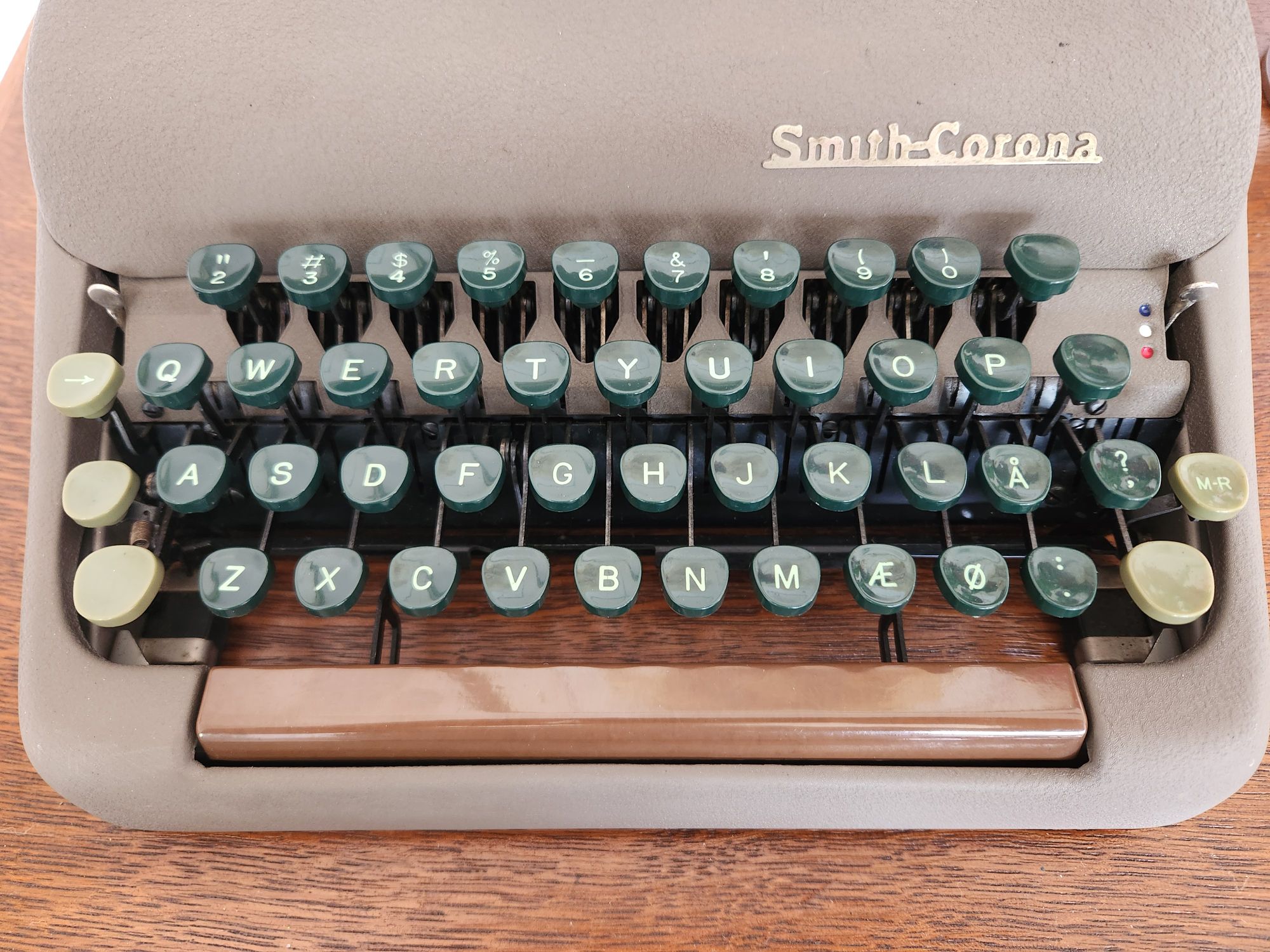 Close up of the dark green plastic keys which comprise the keyboard of the Smith-Corona Clipper. The Shift and shift lock keys are a lighter green and the spacebar is a darker brown than the body of the machine.