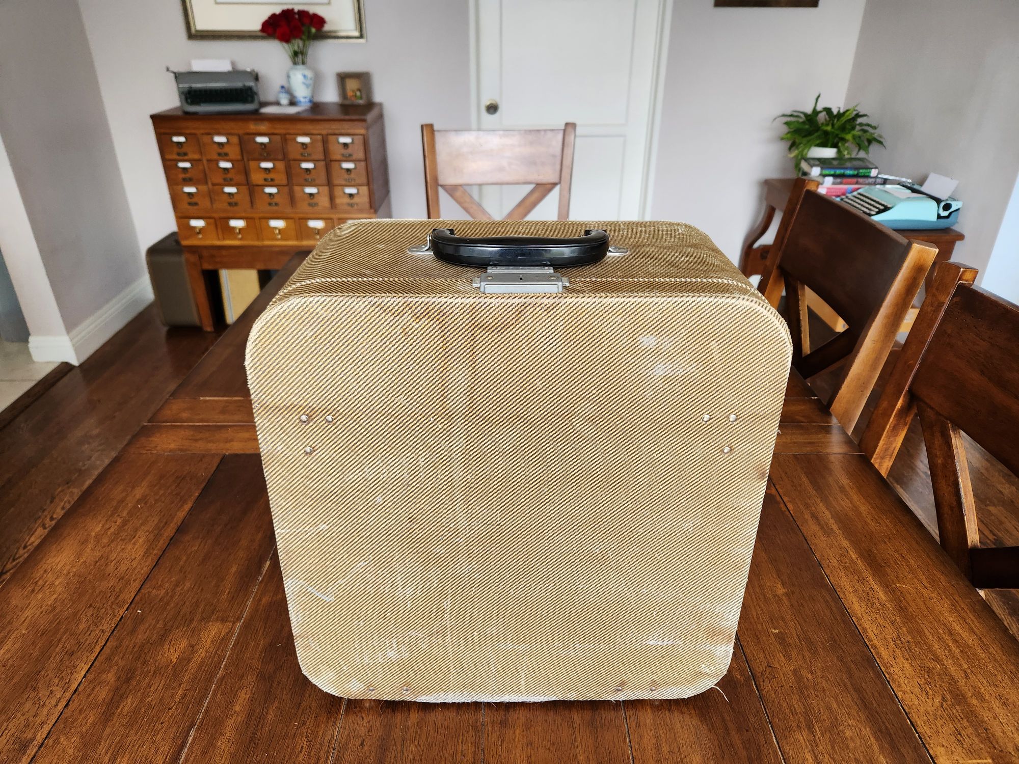 A yellow water-stained typewriter case with a black bakelite handle