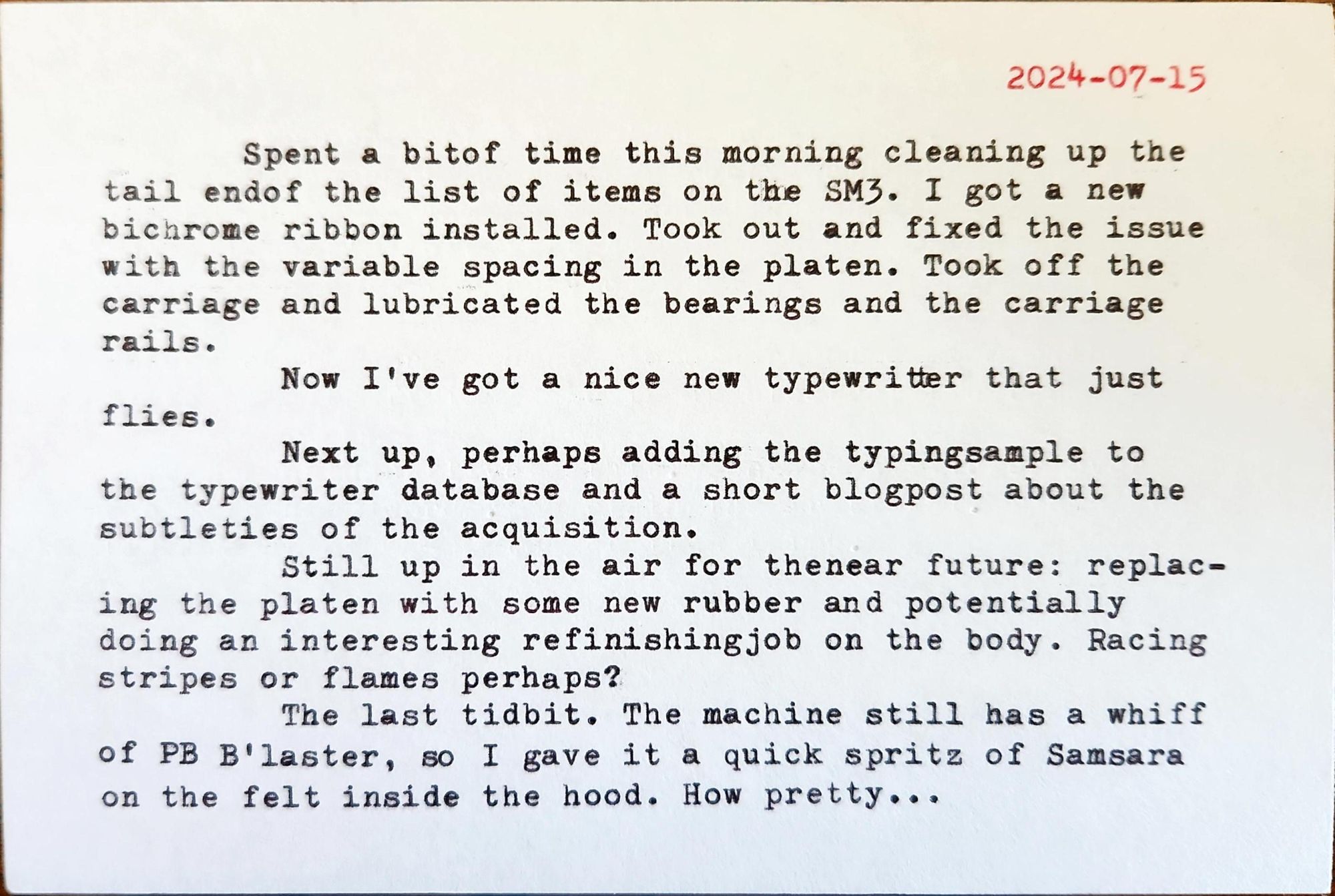 Typed white index card in elite typeface that reads: 2024-07-15 Spent a bit of time this morning cleaning up the tail end of the list of items on the SM3. I got a new bichrome ribbon installed. Took out and fixed the issue with the variable spacing in the platen. Took off the carriage and lubricated the bearings and the carriage rails. Now I've got a nice new typewriter that just flies. Next up, perhaps adding the typing sample to the typewriter database and a short blogpost about the subtleties of the acquisition. Still up in the air for the near future: replac- ing the platen with some new rubber and potentially doing an interesting refinishing job on the body. Racing stripes or flames perhaps? The last tidbit. The machine still has a whiff of PB B'laster, so I gave it a quick spritz of Samsara on the felt inside the hood. How pretty...