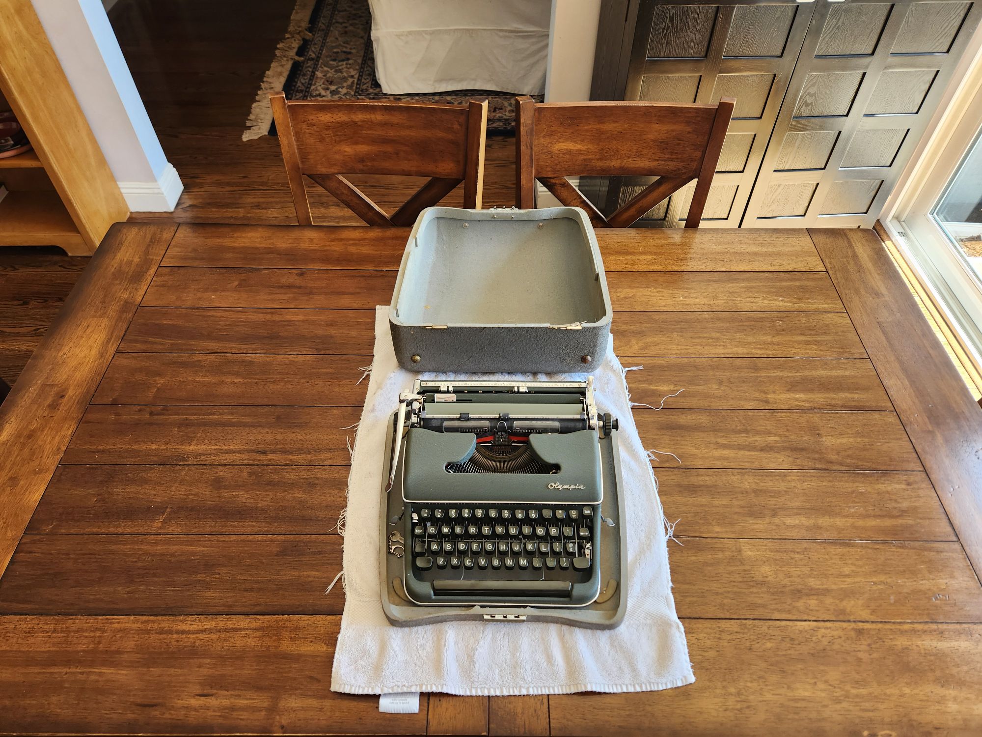 The typewriter case is now open and we see the green dusty typewriter inside it.