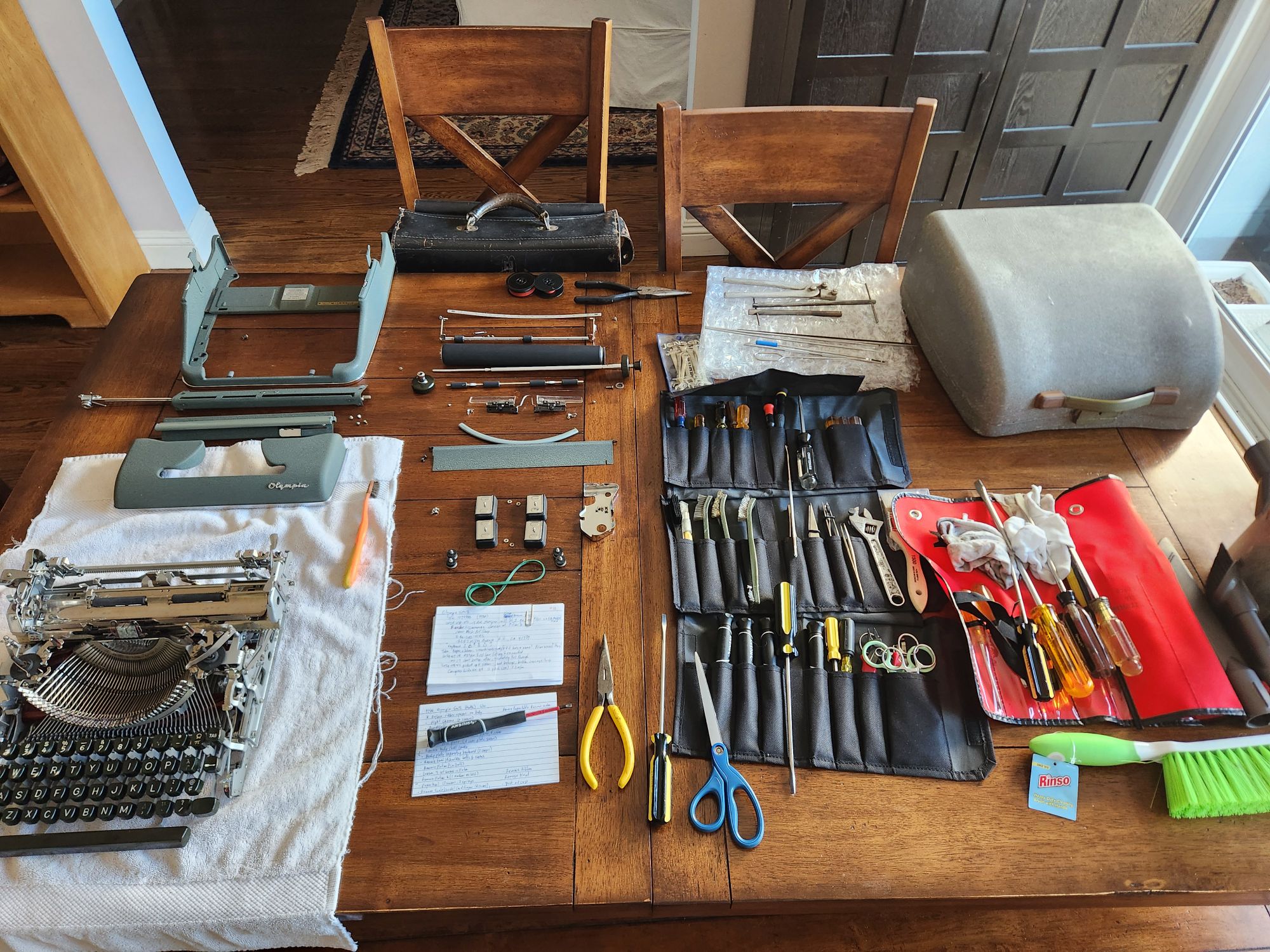 The skeleton of the typewriter sits on the table surrounded by it's parts and screws.