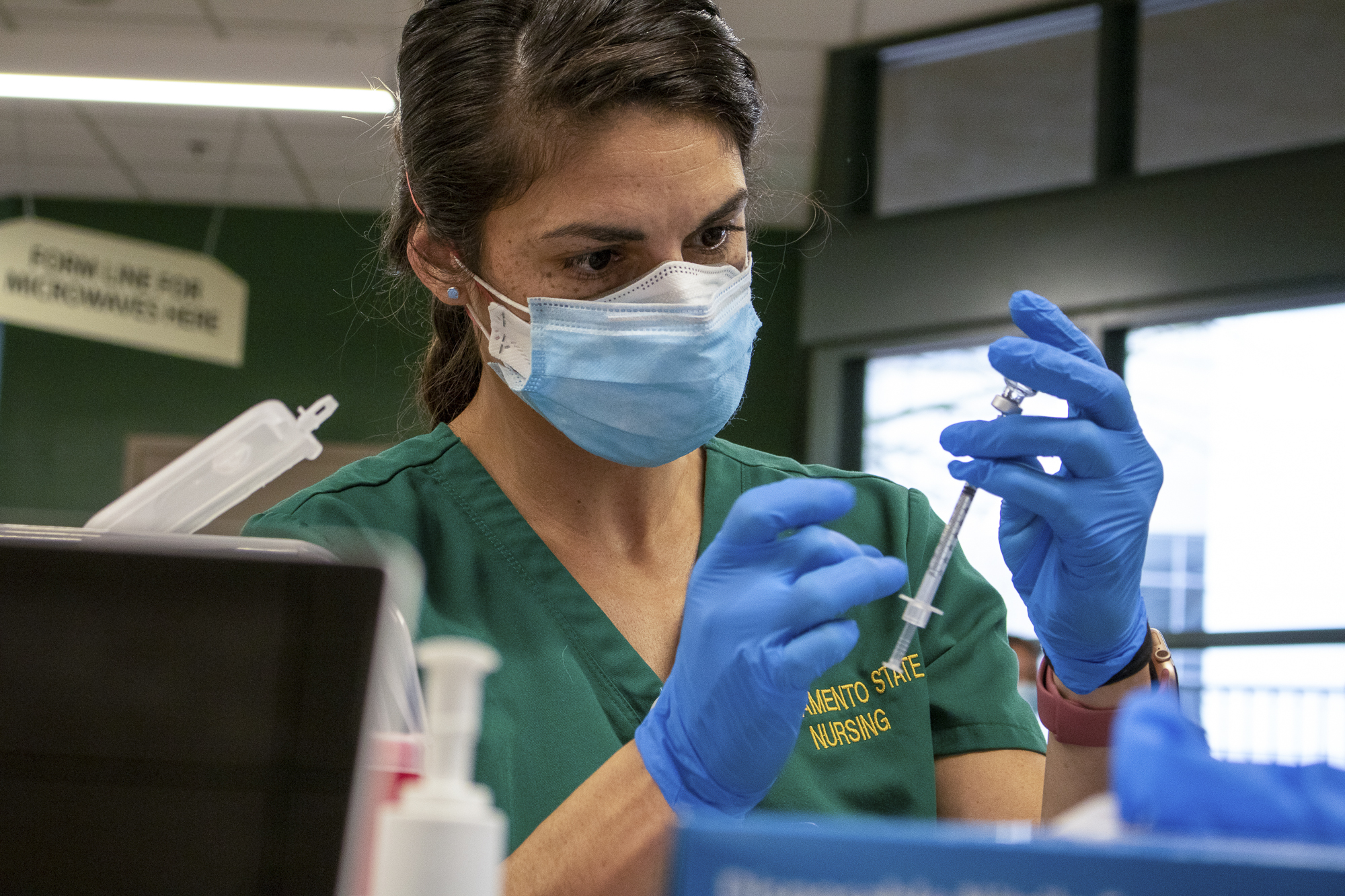 Sacramento State nursing student Amanda Clark fills a syringe with the COVID vaccine at Sacramento State's University Union building on Jan. 29, 2021. Sac State nursing students participate in administering vaccinations to faculty and nursing students. Photo by Rahul Lal for CalMatters  