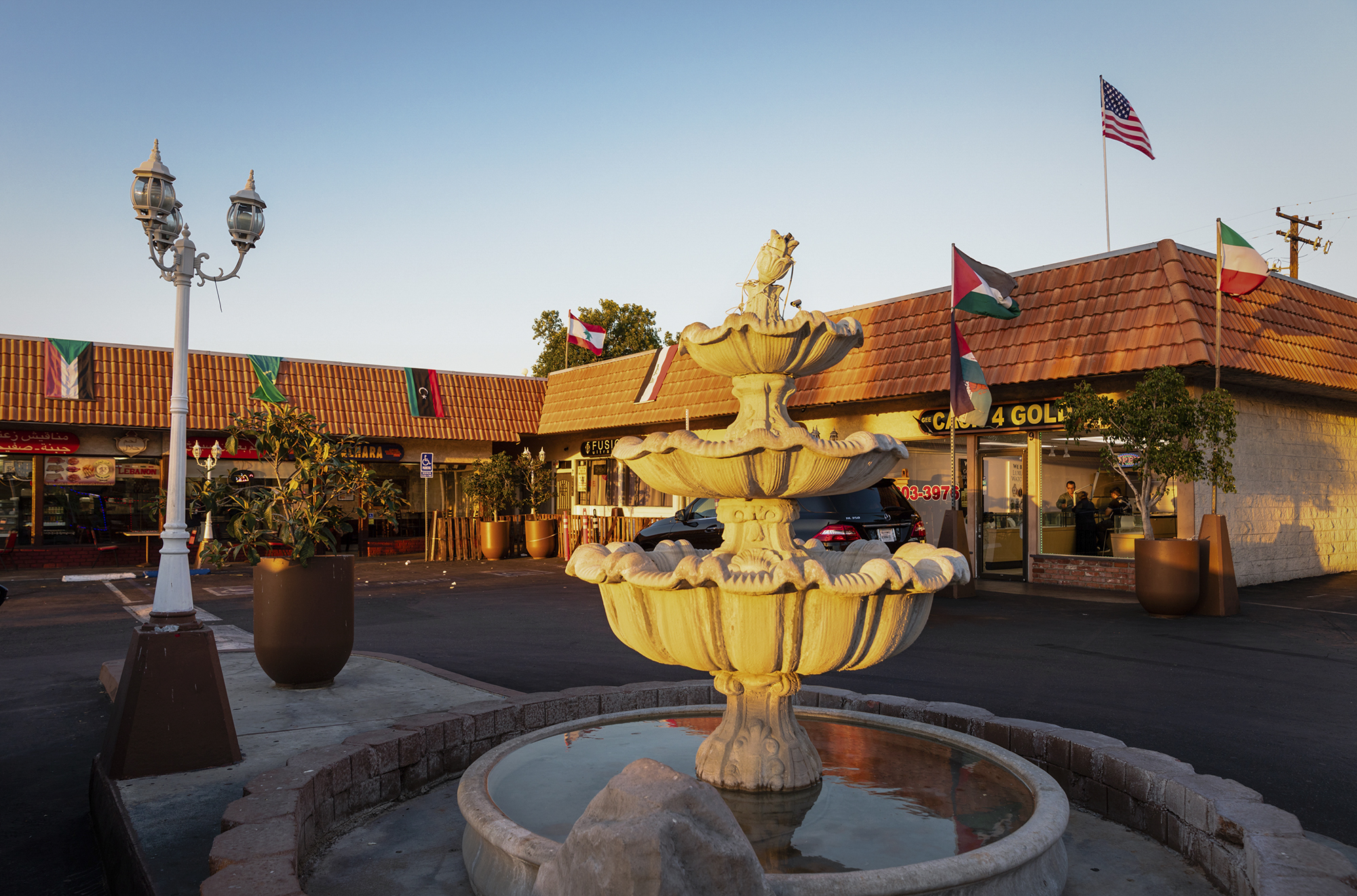 A parking plaza in the Little Arabia neighborhood of Anaheim is adorned with various flags from countries in the Middle East on Oct. 13, 2021. Photo by Deric Mendes for CalMatters
