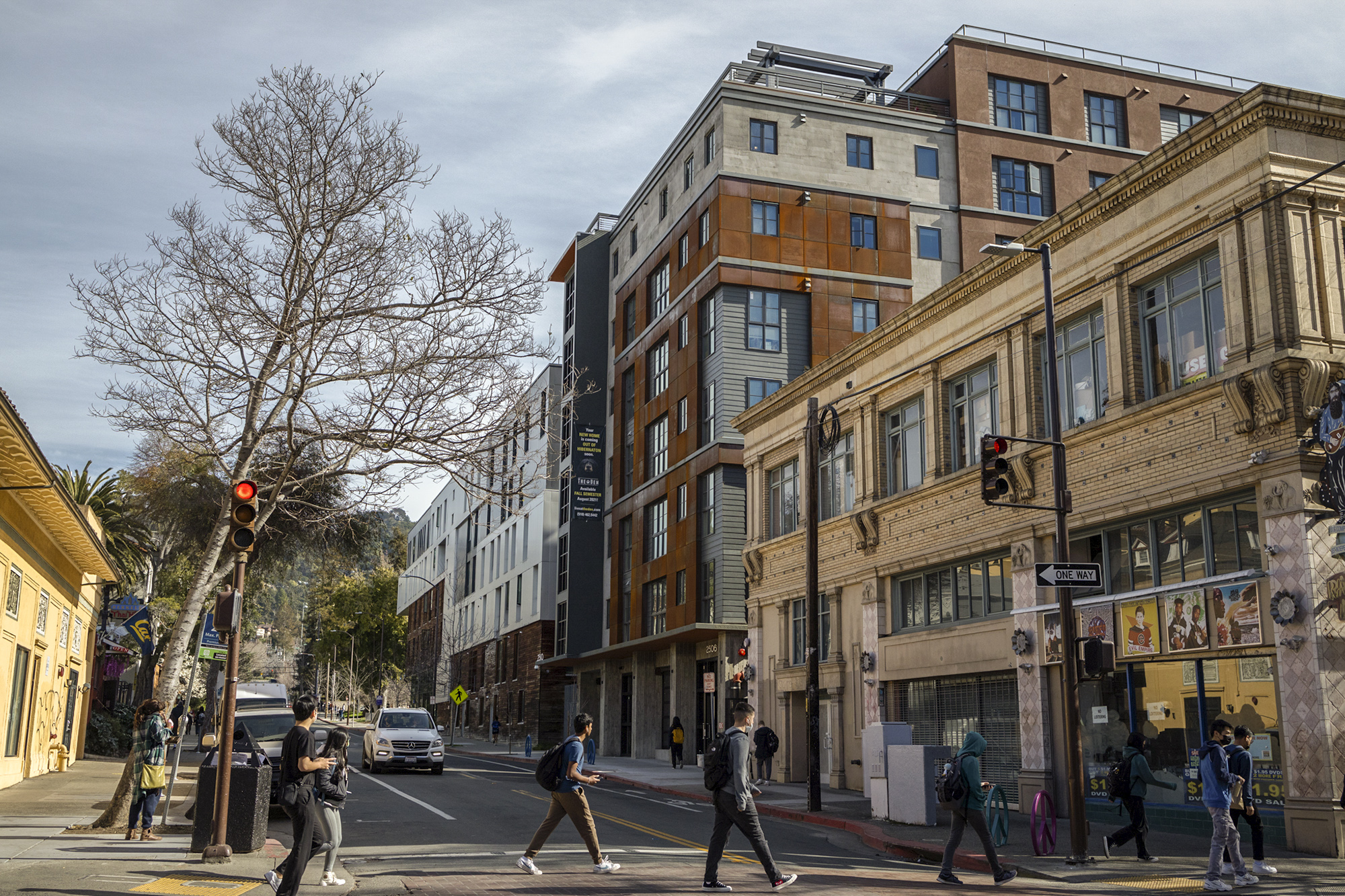 Students walk down Telegraph Avenue with the Den student apartments and Maximino Martinez Commons visible in the background on Feb. 3, 2022. Thalia Juarez for CalMatters