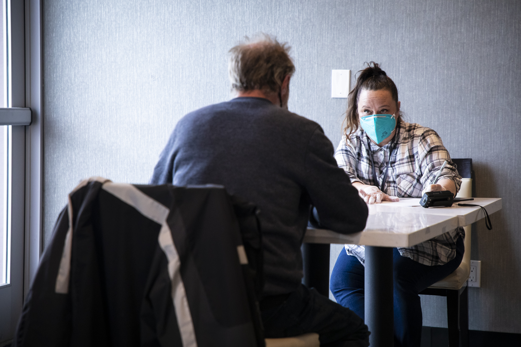 Intake Specialist Annie Wyley meets with a client in the repurposed dining room at the Radisson Hotel on Edes Ave. in Oakland, which is currently occupied by unhoused individuals as part of Project Roomkey on Feb. 9, 2022. Photo by Martin do Nascimento, CalMatters