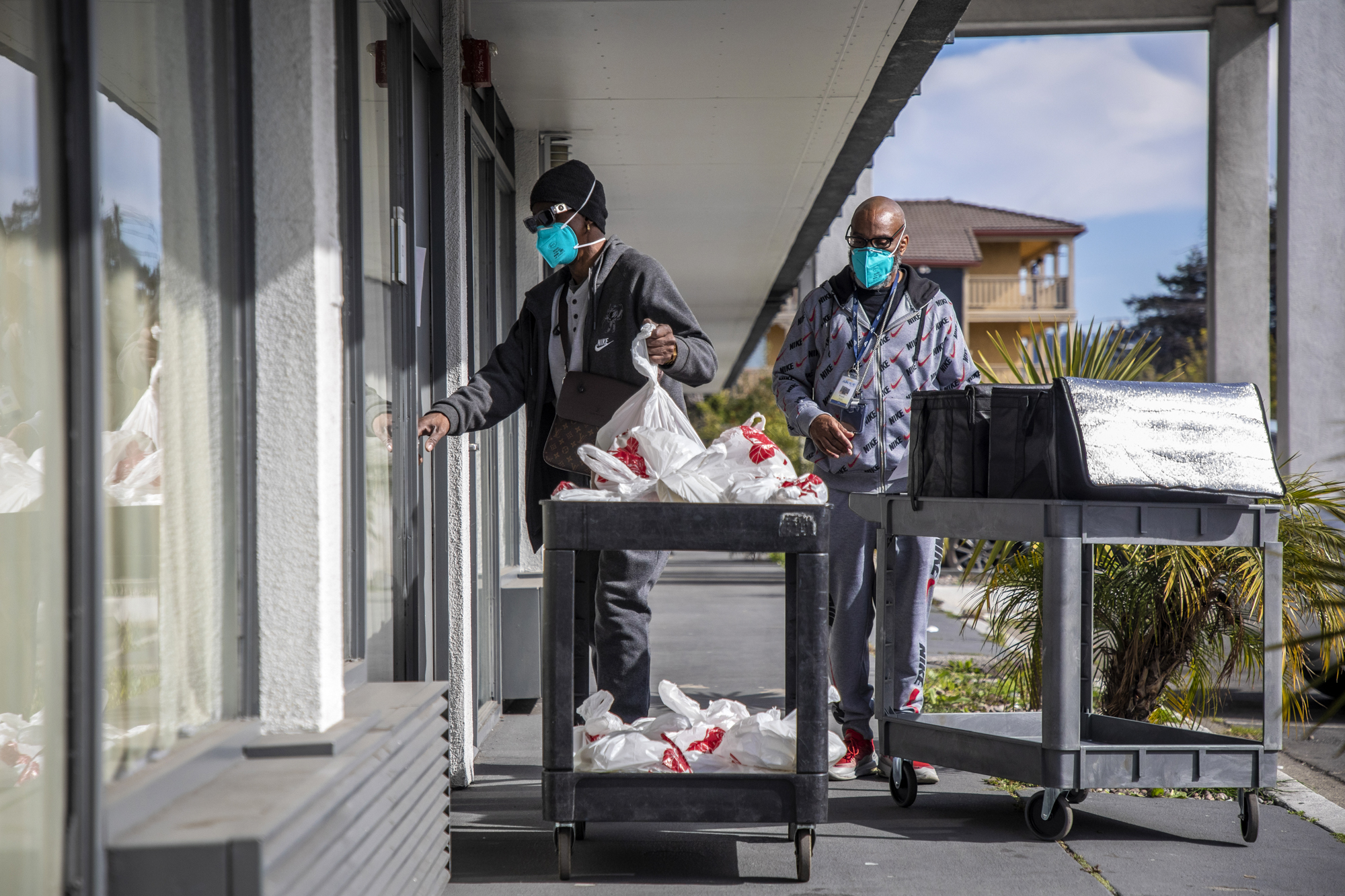 Terry Harper (left) and Frank Scott deliver meals to the unhoused occupants at the Radisson Hotel on Edes Ave. in Oakland, which is currently occupied by unhoused individuals as part of Project Roomkey on Feb. 9, 2022. Photo by Martin do Nascimento, CalMatters
