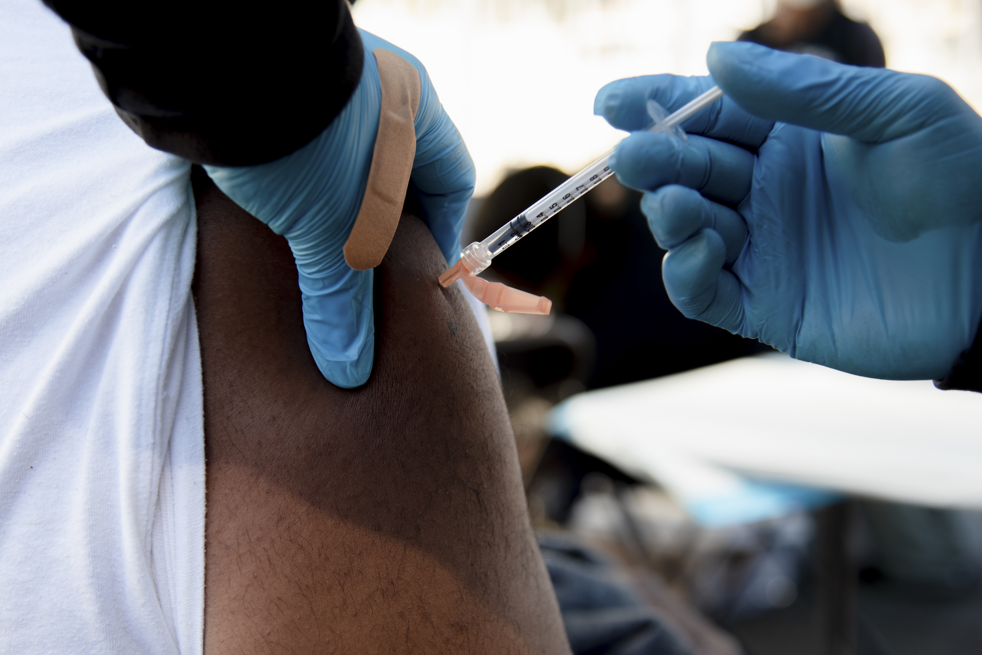 Deondray Moore, 35, receives the COVID-19 vaccine at Umoja Health pop-up clinic in Oakland on Thursday, February 17, 2022. Mr. Moore says he decided to get vaccinated so that he could join his partner in the hospital room when their first child is born in June. Photo by Marissa Leshnov for CalMatters
