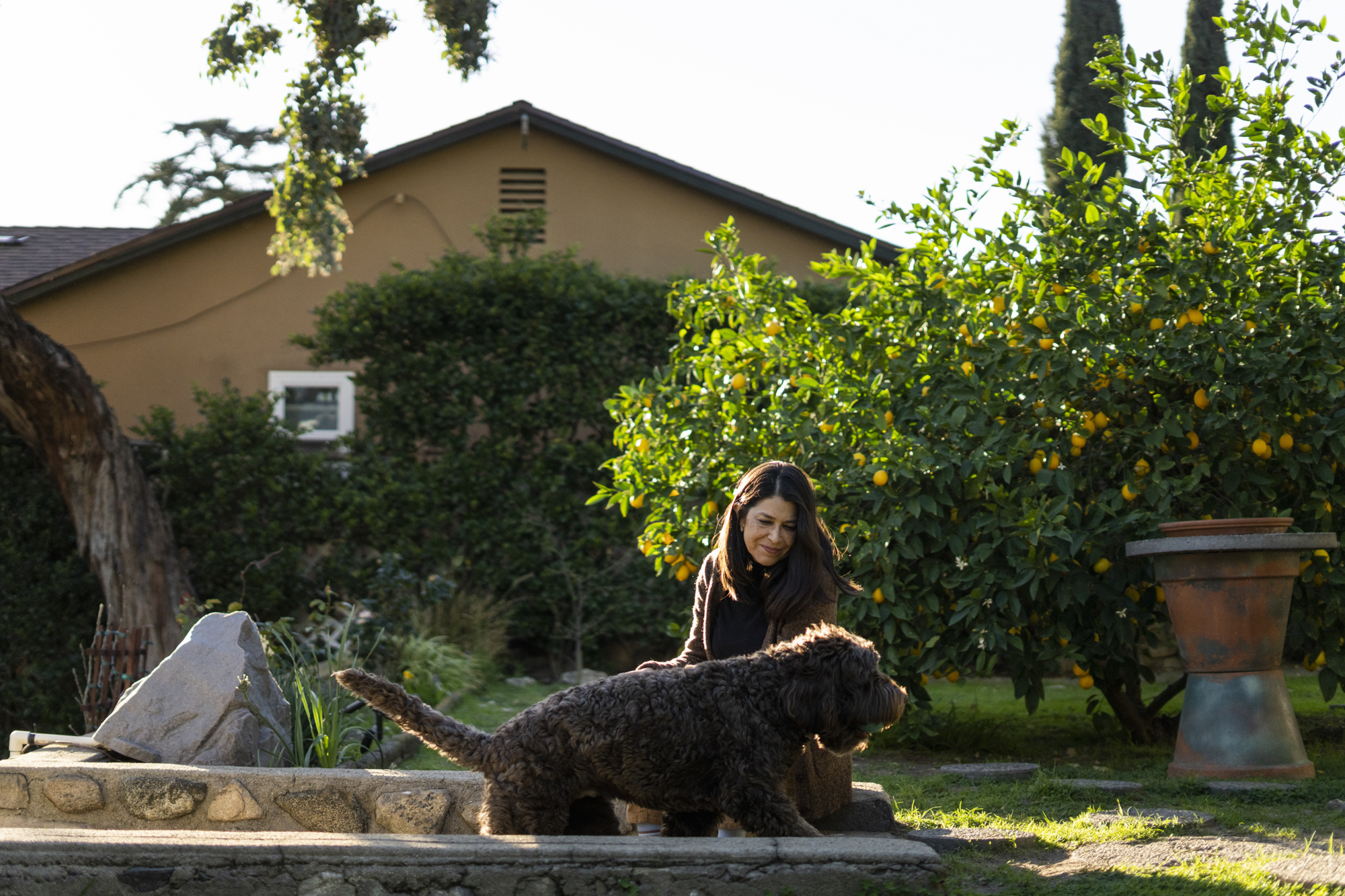 Renata Garza-Silva plays with her dog in her backyard Thurs. Feb. 17, 2022. Garza is immunocompromised and is at risk from lifting the mask mandate. Photo by Lauren Justice for CalMatters