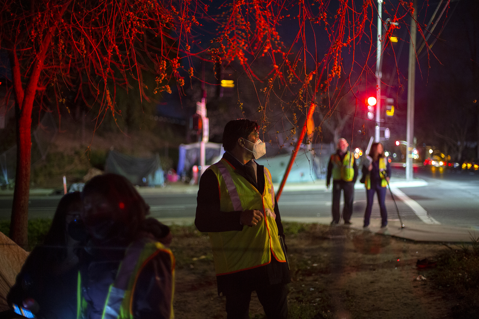 Volunteers walk near a homeless camp in Sacramento during the city's point-in-time count of the unhoused population on Feb. 24, 2022. Photo by Miguel Gutierrez Jr., CalMatters