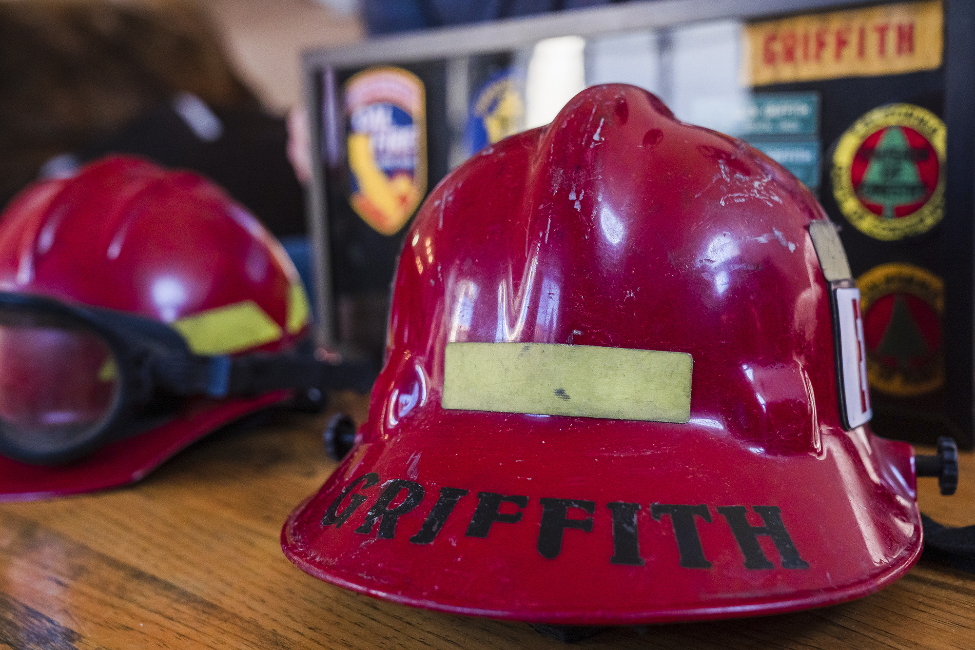 Jeff Griffith's structural helmet (left) and wildland fire helmet (right) on a table in his living room in Escondido on Feb. 10, 2022. Photo by Ariana Drehsler for CalMatters