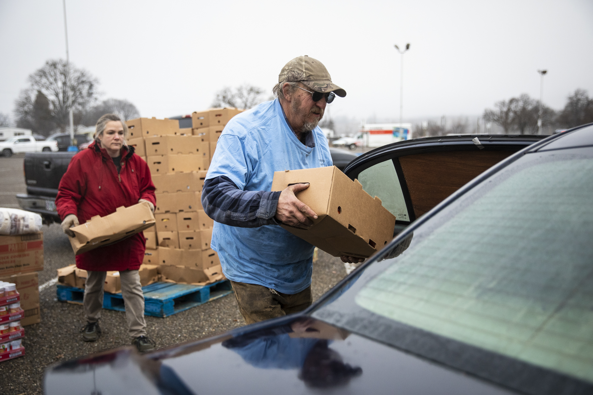 Volunteers Terry Scovil, center, and Shendi Klopfer load the car of a community member with food from the Trinity County Food Bank at the Trinity County Fairgrounds on Feb. 8, 2023. 