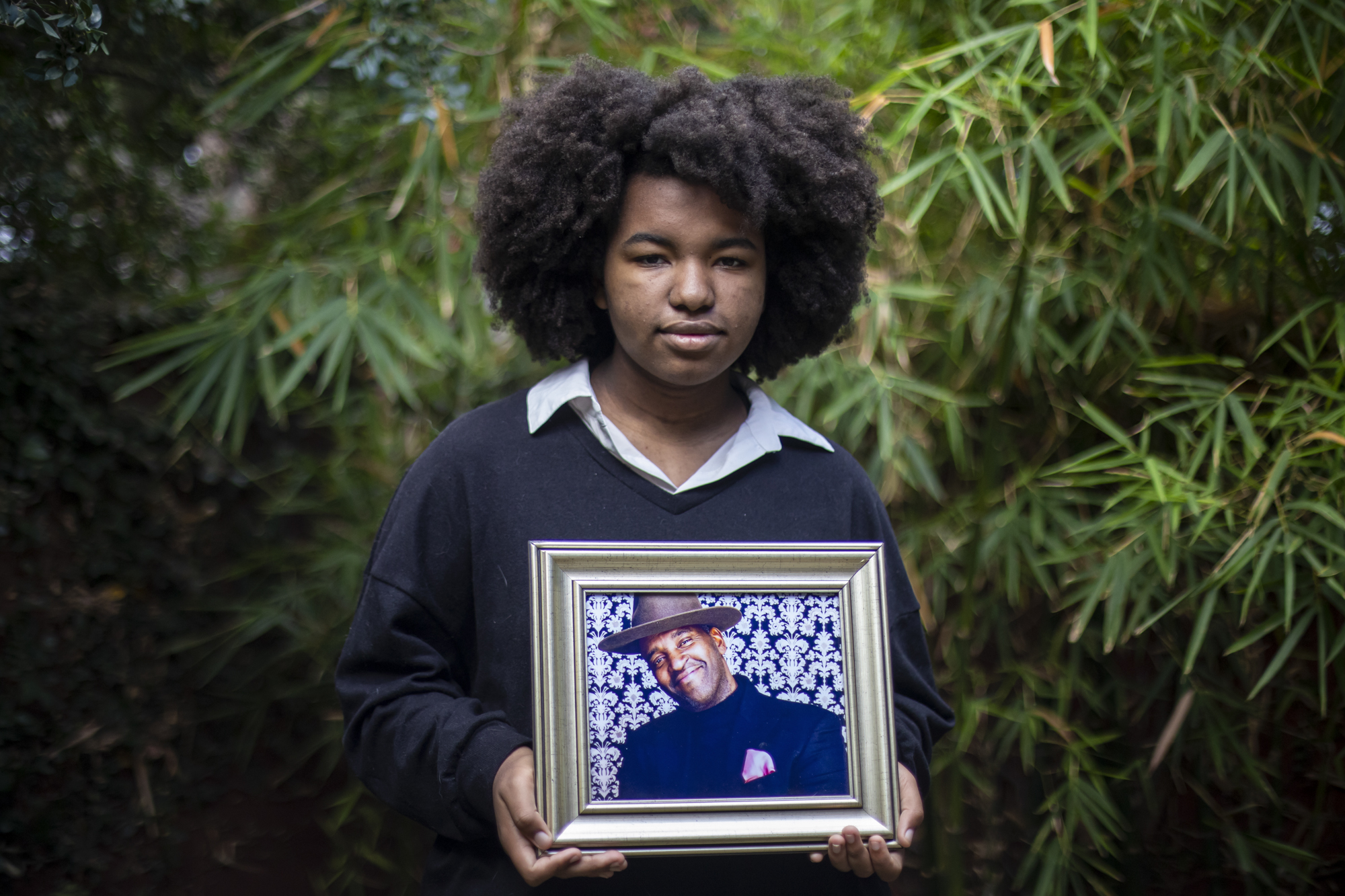 MacLemore Porter, whose father died of COVID, holds a portrait of him in her backyard in Bakersfield