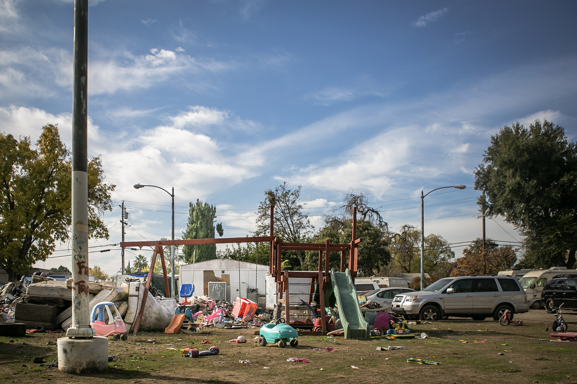 Discarded mattresses and other trash encroach on a playground at Stockton Park Village in the outskirts of Stockton on Nov. 22, 2022. Bobby Riley, 87, said he bought the swing set for his granddaughter but will soon have to take it down because the garbage hasn't been picked up for months.