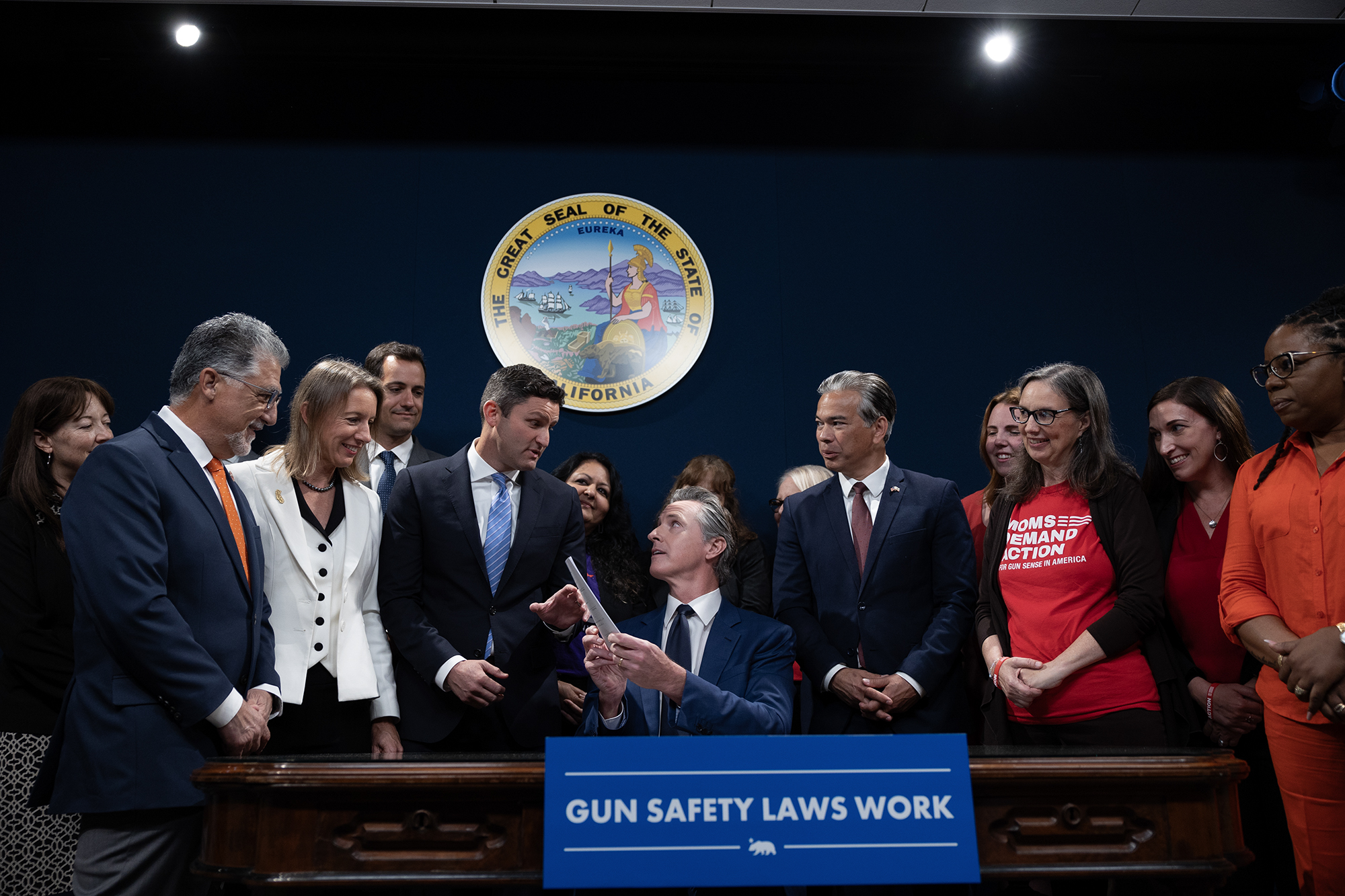 Flanked by lawmakers and gun safety advocates, Gov. Gavin Newsom signs new gun legislation into law at the Capitol annex in Sacramento on Sept. 26, 2023. Photo by Miguel Gutierrez Jr., CalMatters