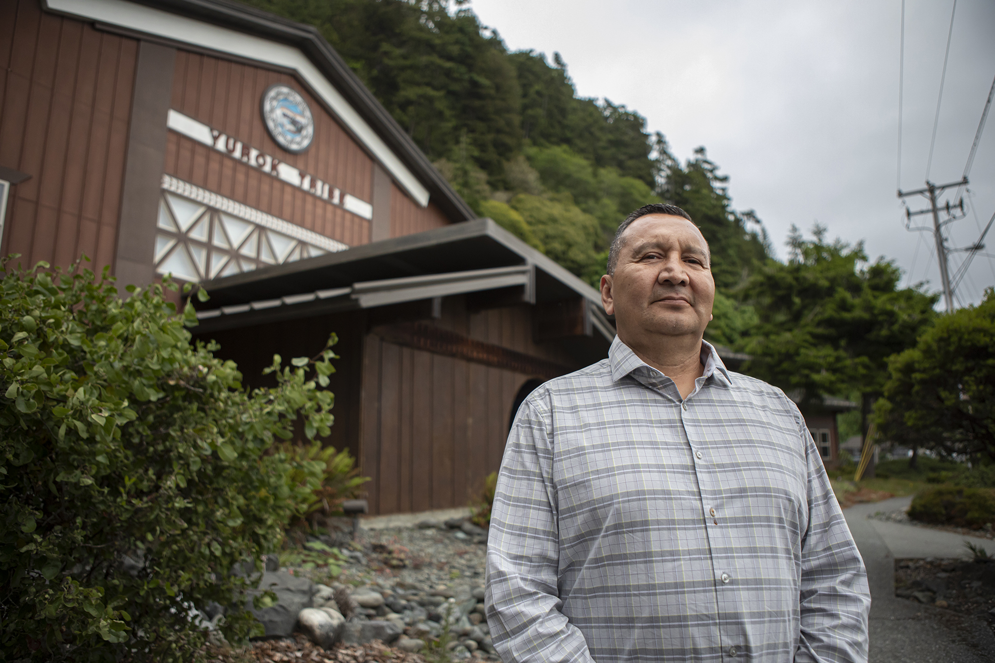 Philip Williams, a member of the Yurok tribal council, stands at the main entrance of the Yurok Tribe Headquarters on June 7, 2023. Williams is concerned about what the offshore wind turbines could mean for the jobs and economy of the people in Yurok. Photo by Larry Valenzuela, CalMatters/CatchLight Local