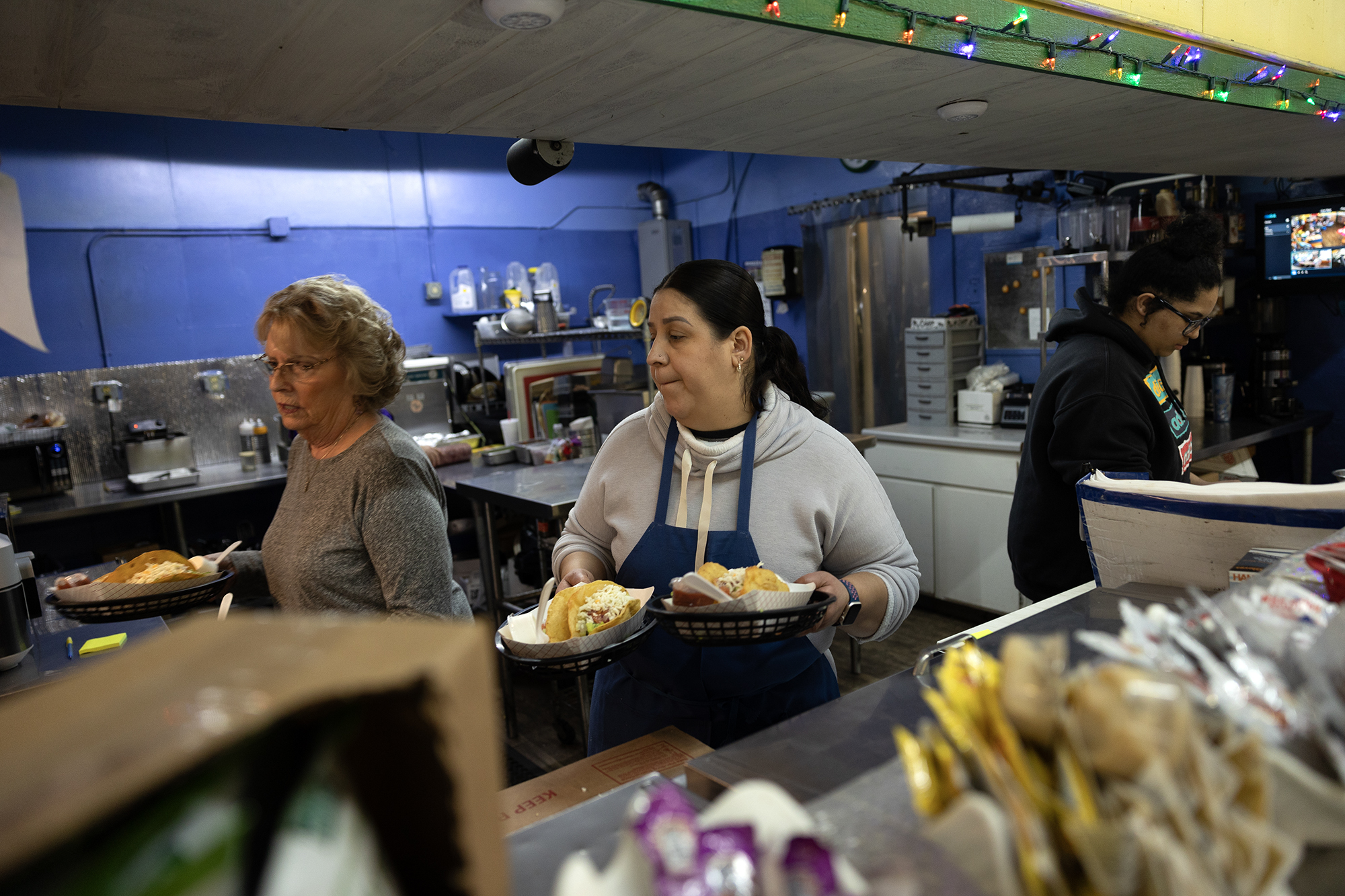 From left, Sue Bird, Jilary Barba and Hannah Vinson work during the lunch rush at the Big Valley Market in Bieber on Jan. 30, 2024. In 2023, the Babcocks, who own Big Valley Market, paid Pacific Gas & Electric nearly $40,000 for electricity — about two-thirds of the store’s annual profit. This year rates for businesses their size will grow by 17%. Photo by Miguel Gutierrez Jr., CalMatters
