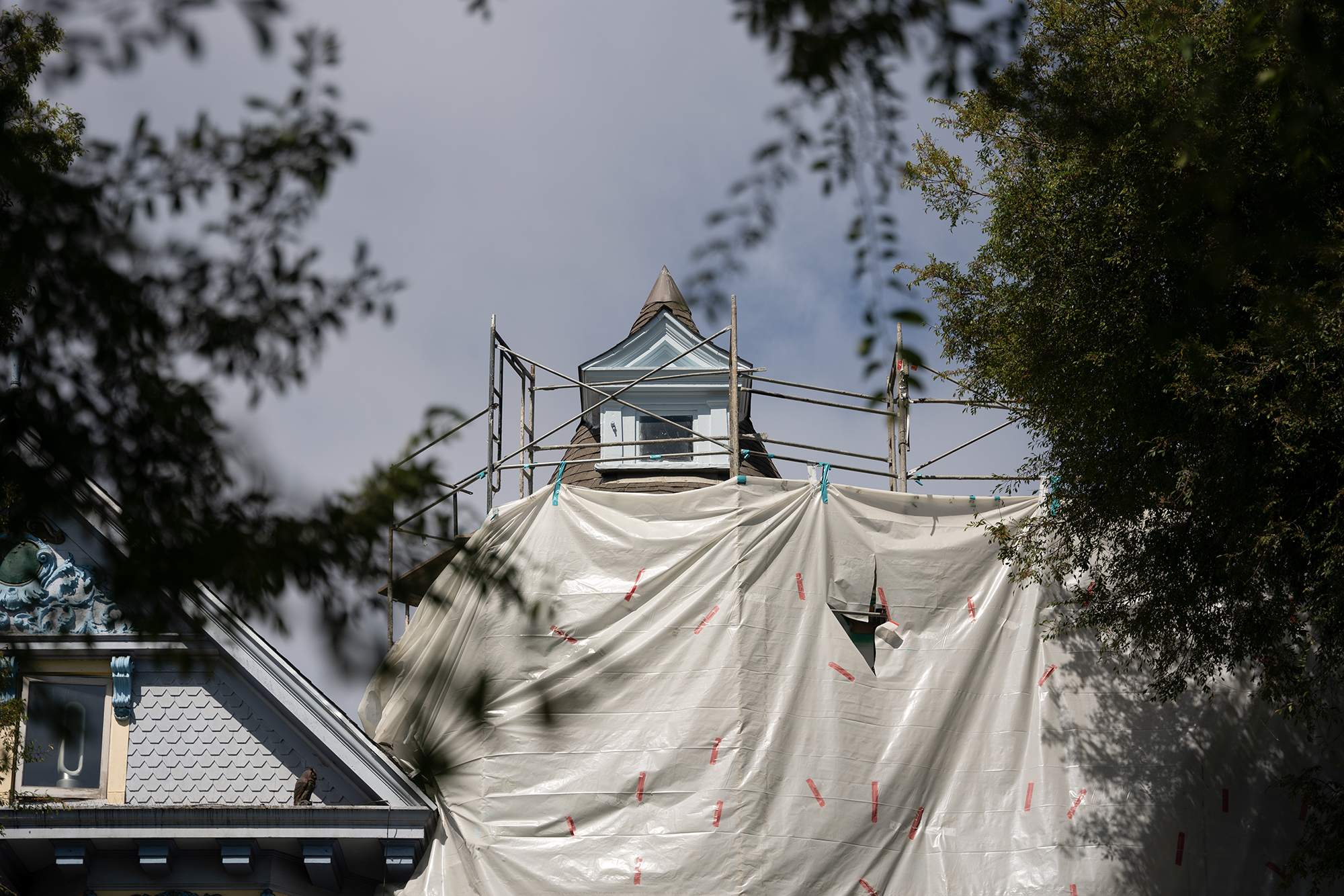 A house is surrounded in a construction tarp.