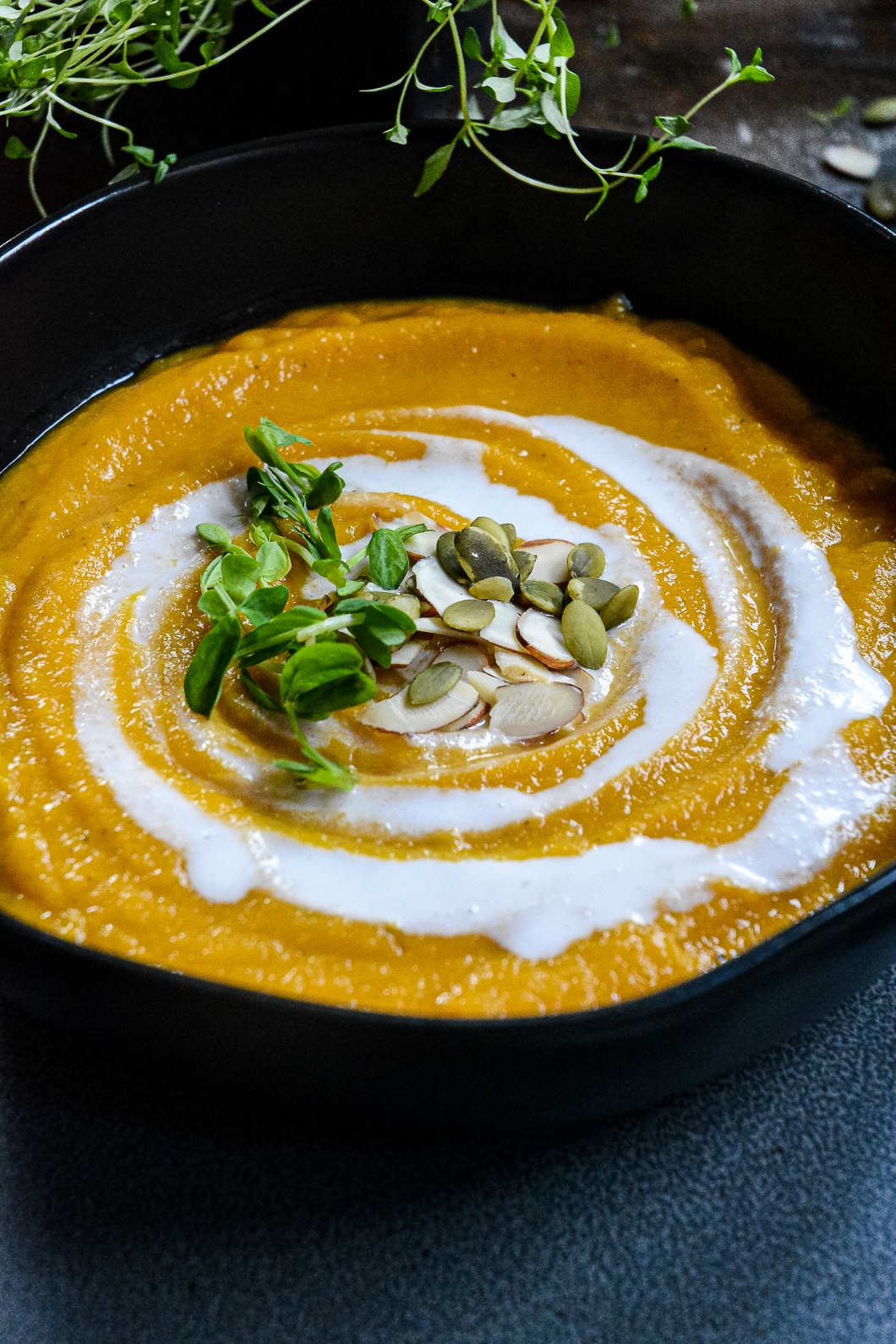 Squash soup up close with coconut cream swirl and pumpkin and almonds