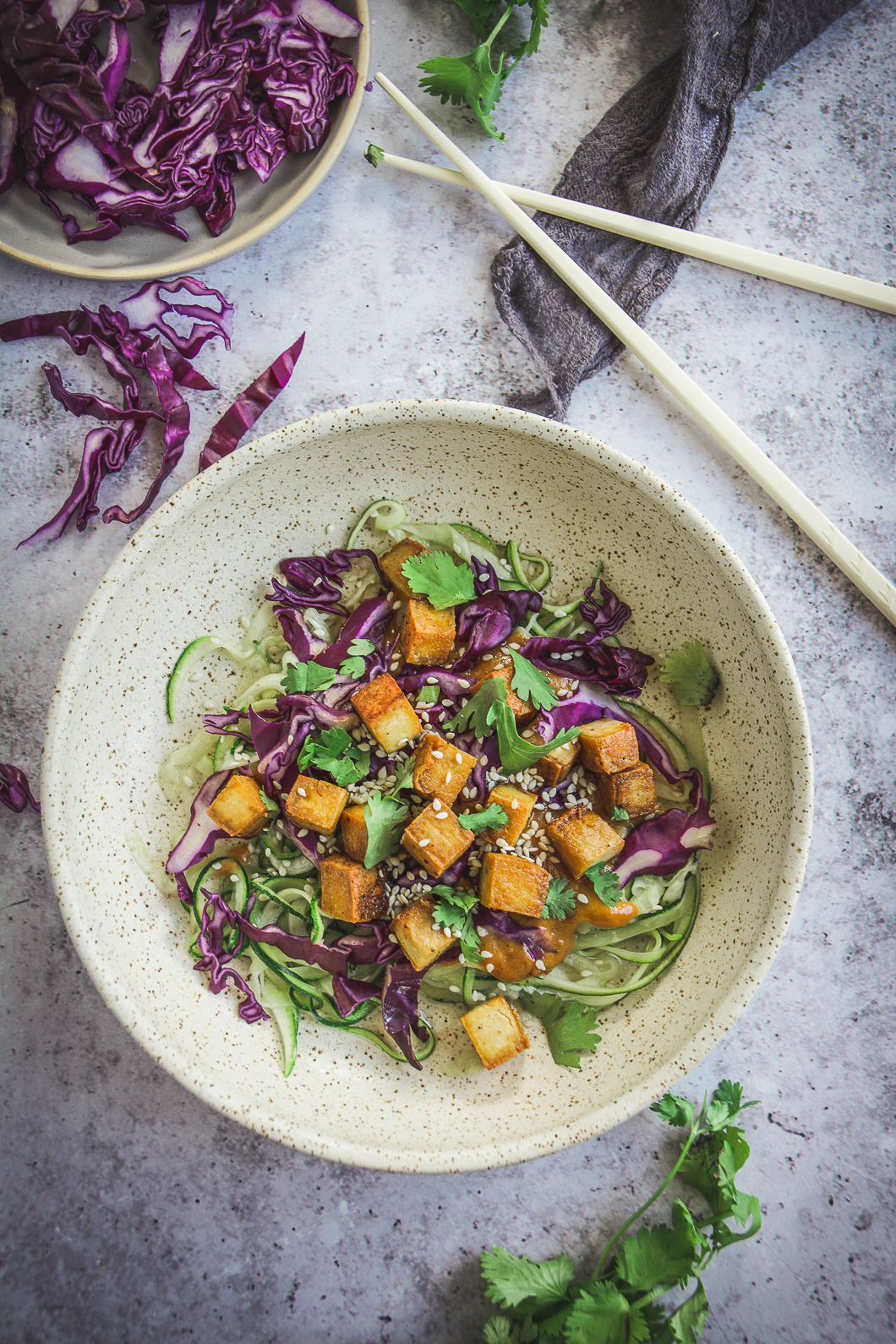 Zoodles with Thai Peanut Sauce and Tofu on table with cilantro and chopsticks
