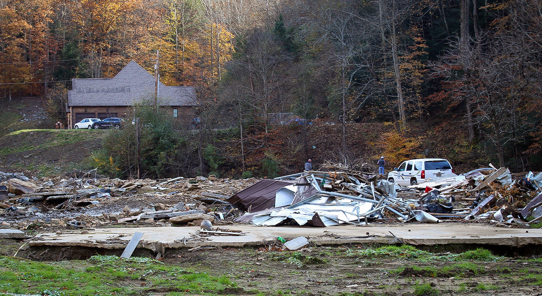 Two men walk through the site of a house leveled by flooding in Hurley