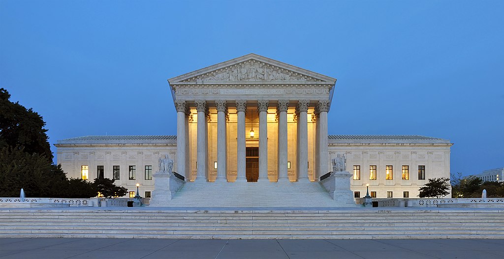The building housing the United States Supreme Court is lit up at dusk.
