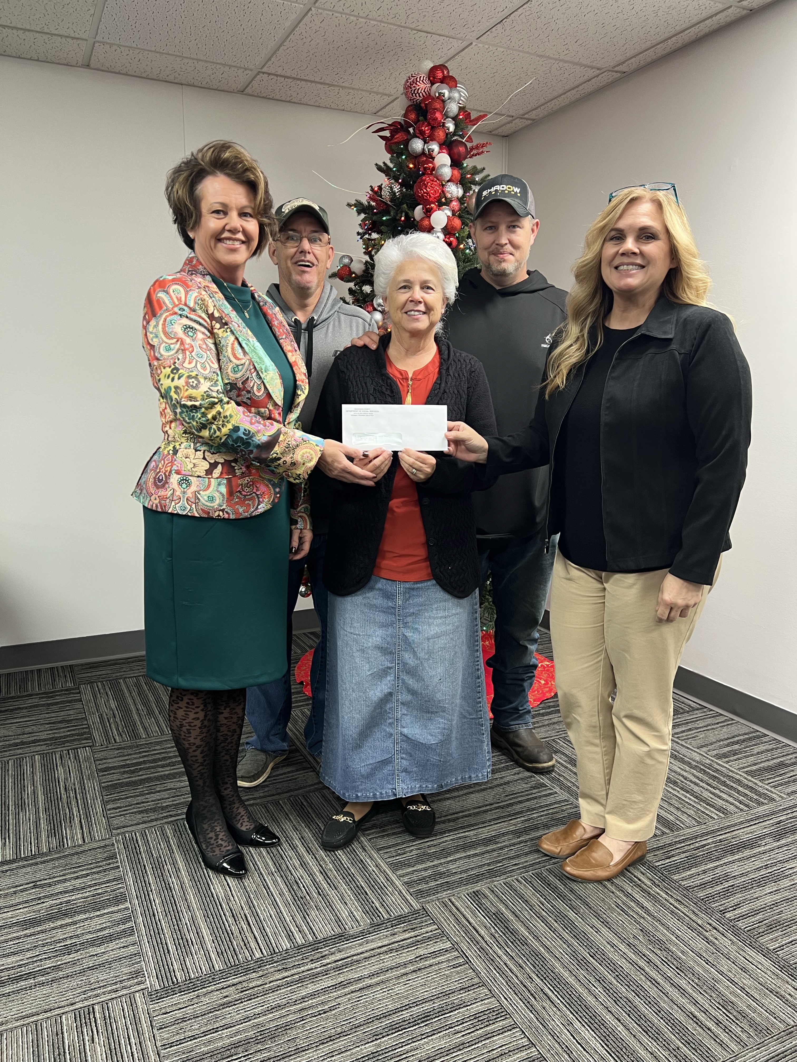 Barbara Blankenship Coleman, center front, is the first recipient of compensation for damage to her property during the devastating 2021 Hurley flood. To the left is Marci Watson, executive director of the Buchanan County Department of Social Services, which is administering the distribution of an $11 million state assistance fund; at right is Denise McGeorge, DSS program coordinator.  In the back are Coleman’s two sons, Robert Burns Blankenship and Timothy Eugene Blankenship. Courtesy of Buchanan County DSS and The Voice newspaper.