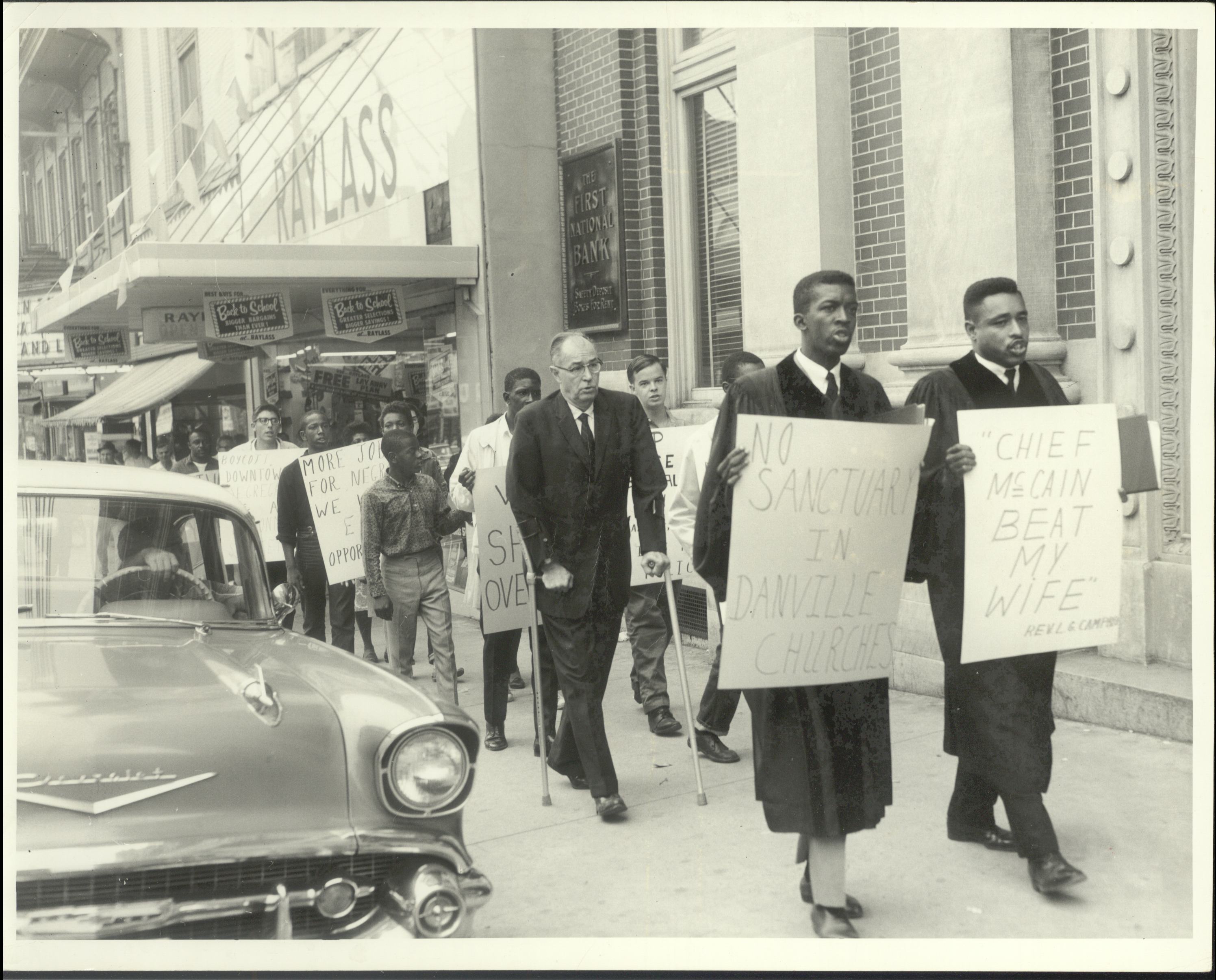 Protesters holding signs walk down a sidewalk in downtown Danville. 