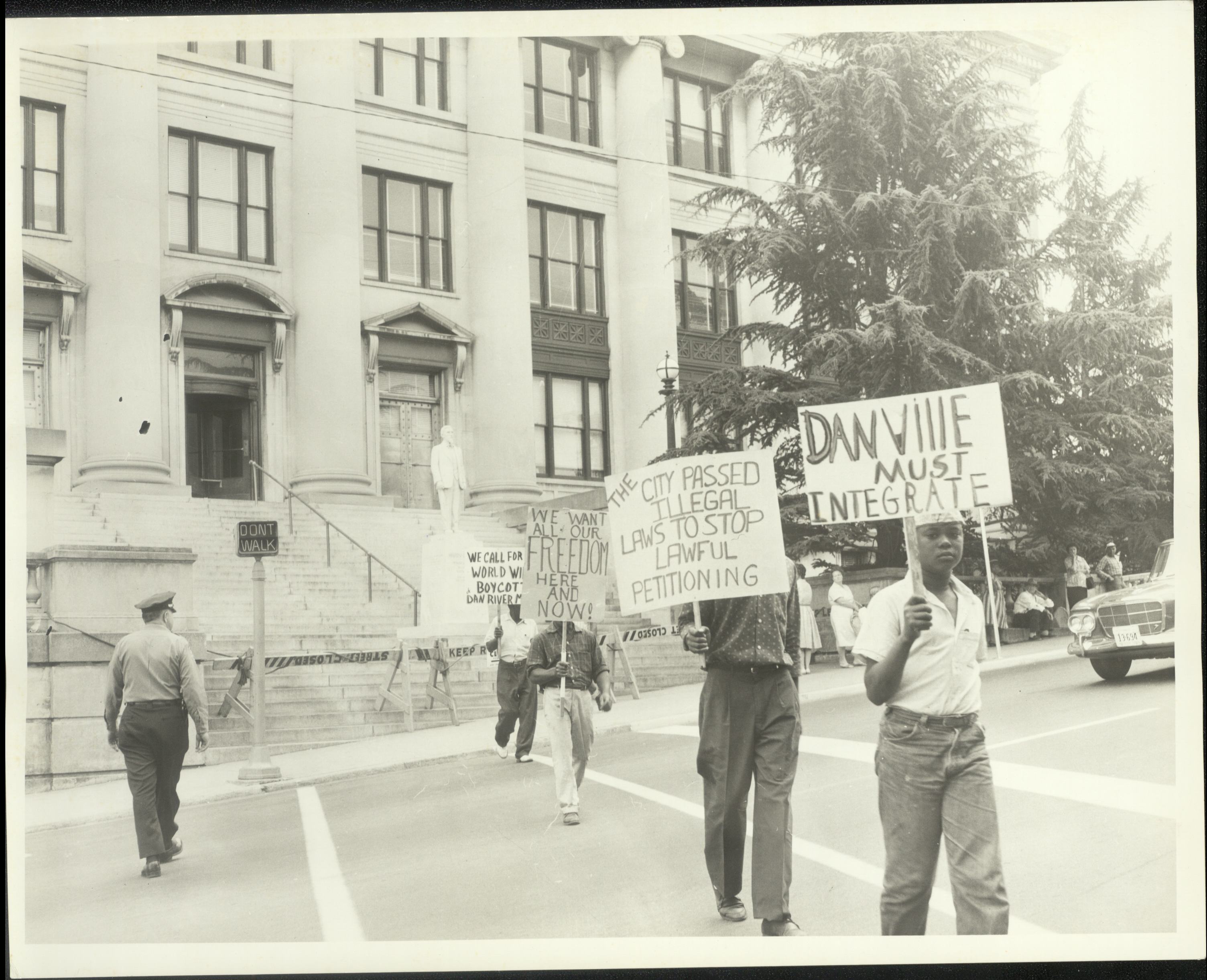 Several people picket in front of a building in Danville holding signs that say "Danville must integrate" and other sayings