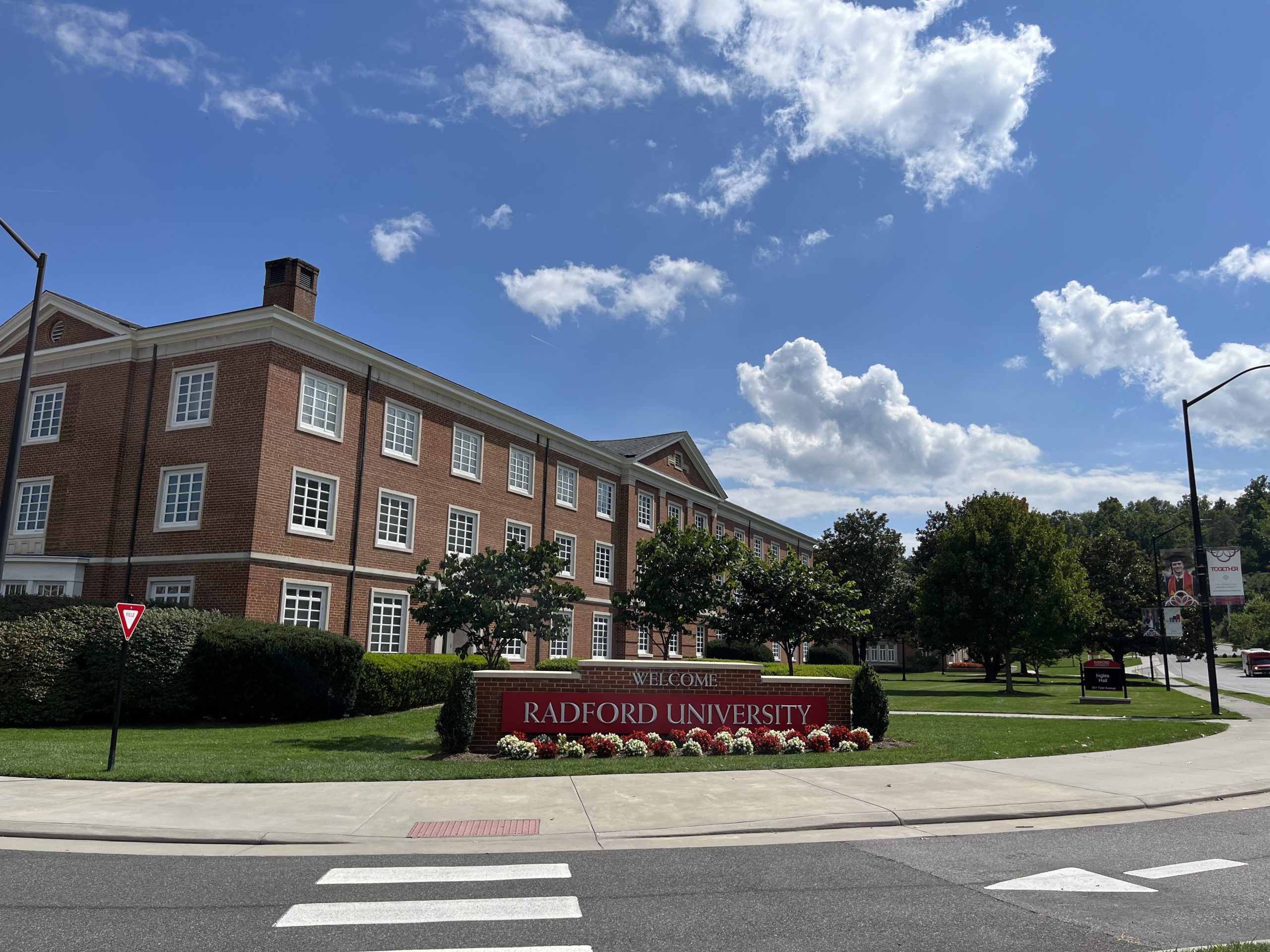Three-story red brick building on a green lawn, with "Radford University" sign in front.