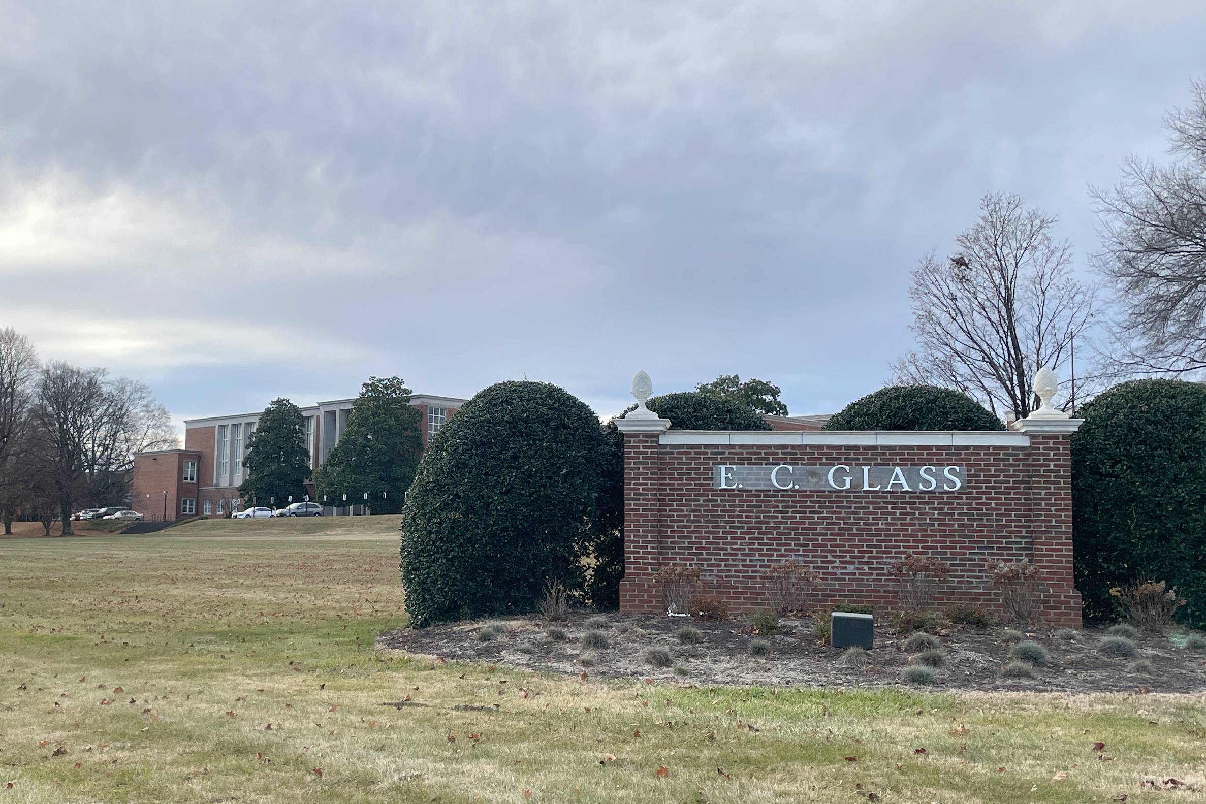 A brick sign that reads "E.C. Glass High School" in front of a school building.