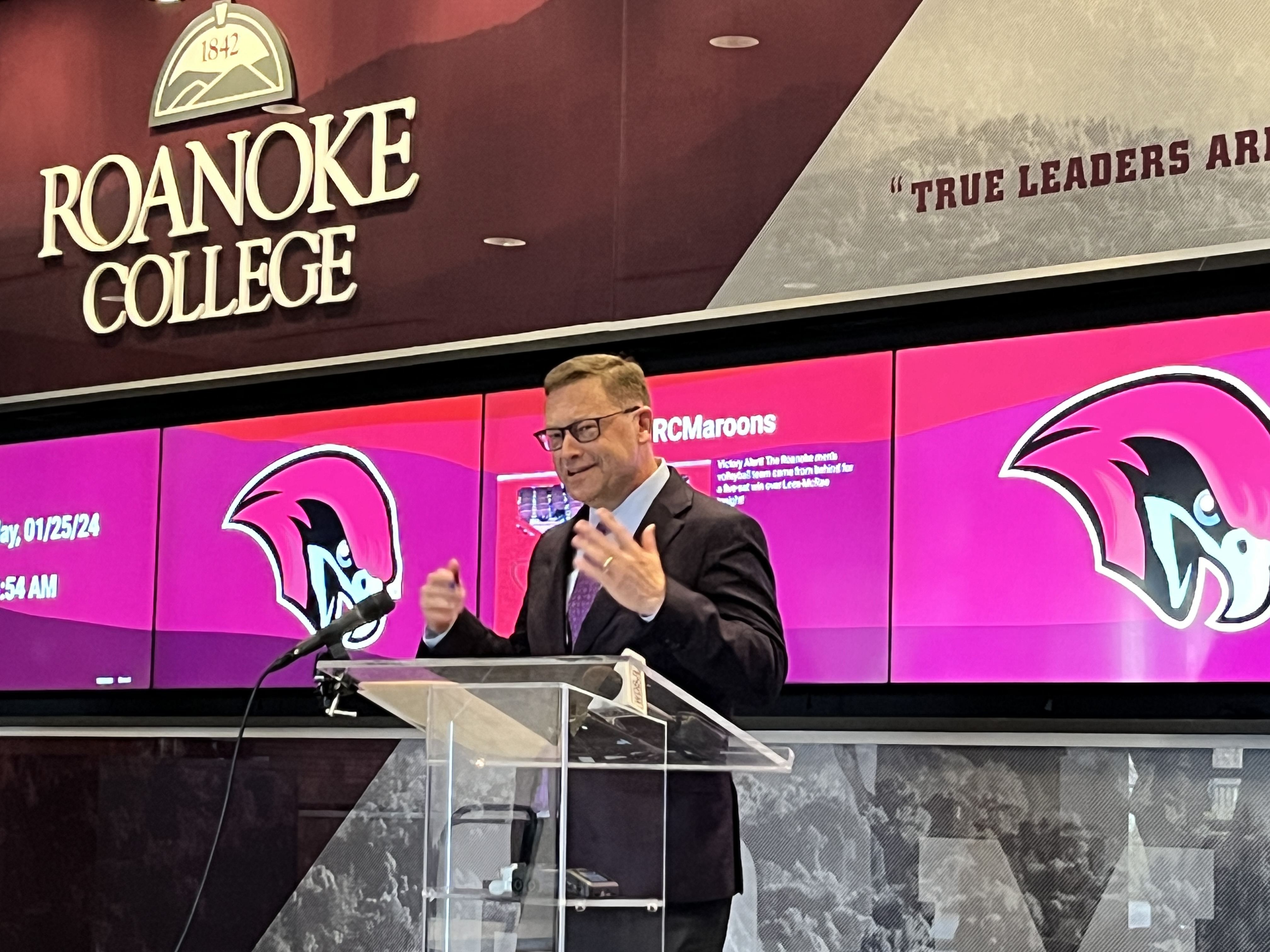 Roanoke College President Frank Shushok at a lectern in front of a Roanoke College Maroons banner.