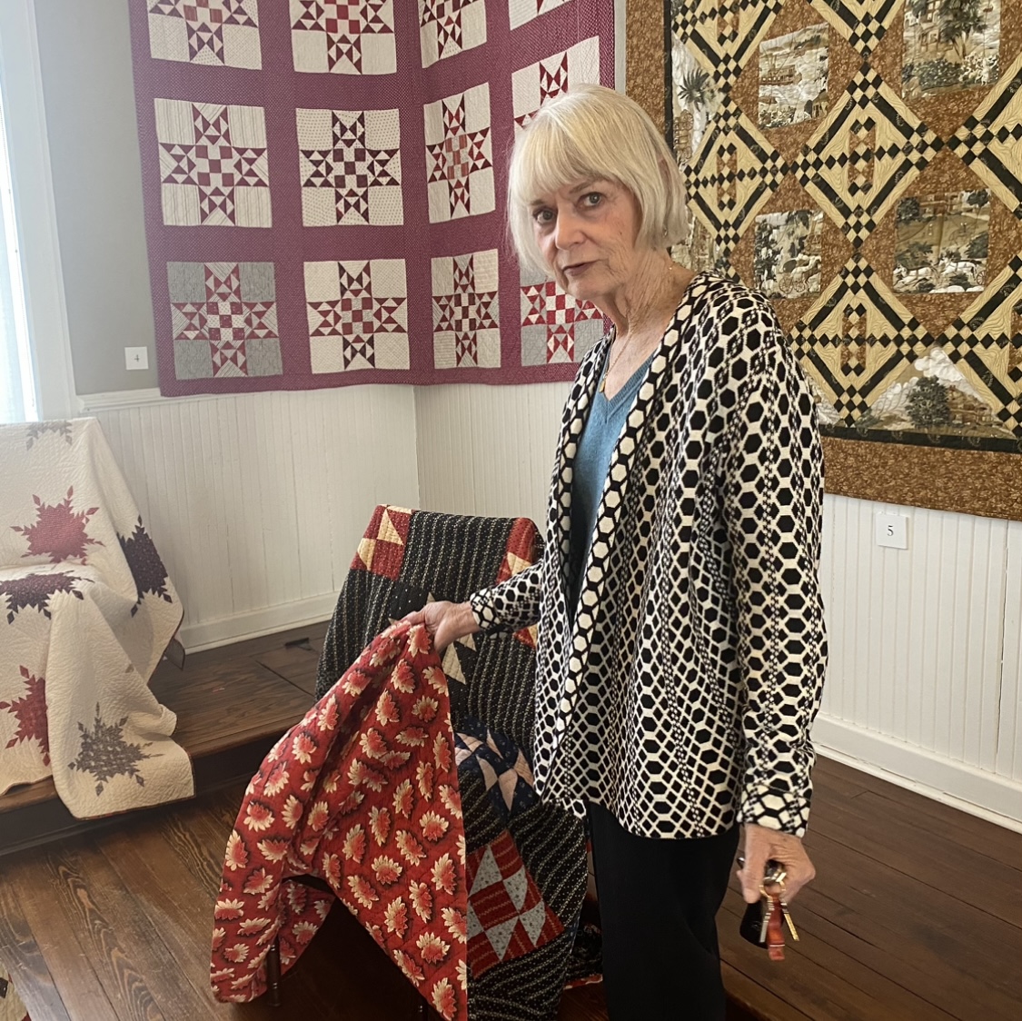 Gayle Hillert, past president of the Masonic Theatre Preservation Foundation, shows off an antique quilt at the exhibit. Photo by Shauna Muckle
