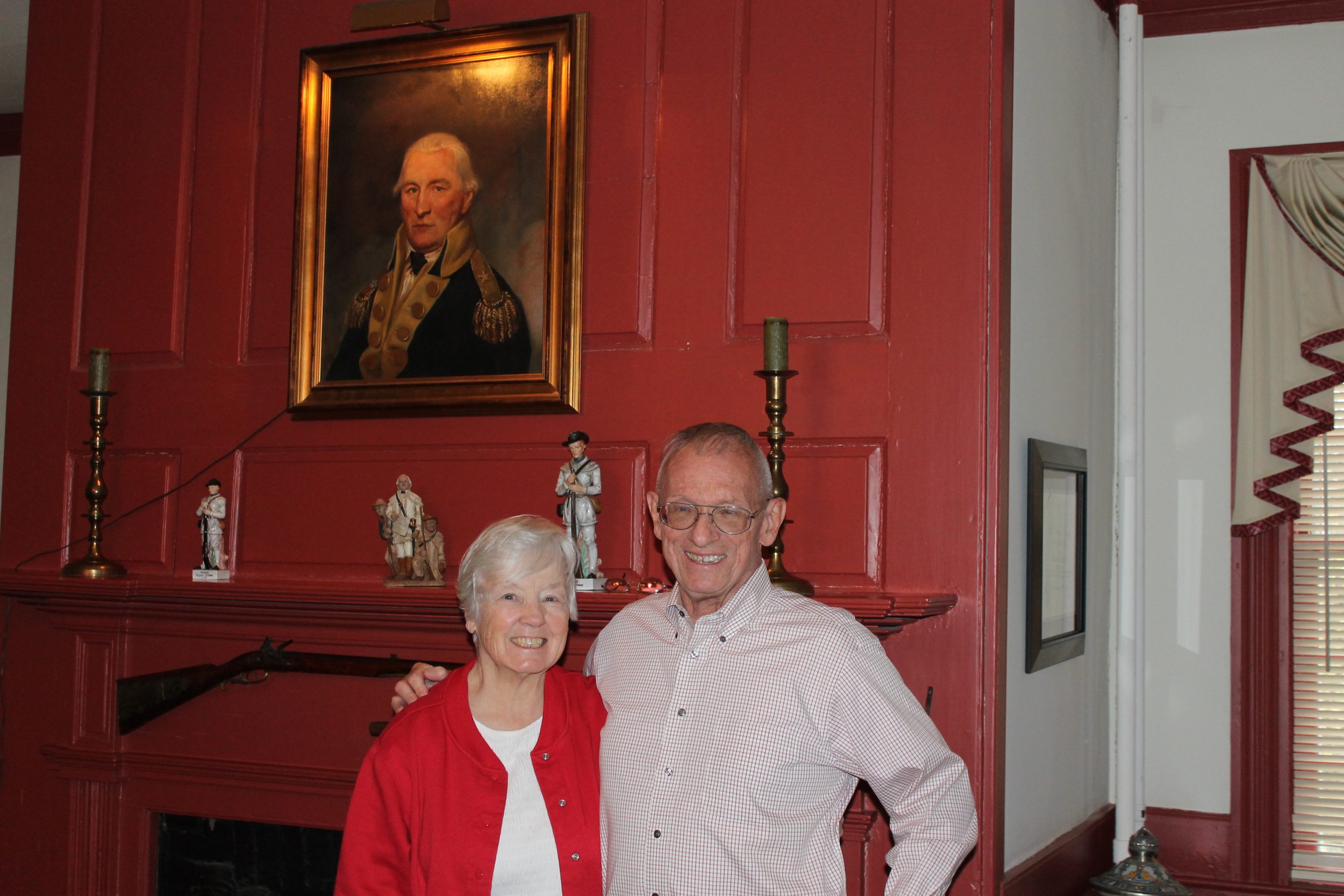 1. Daniel Morgan looks on as Jeanne and George Schember pose in front of one of the 10fireplaces in their home