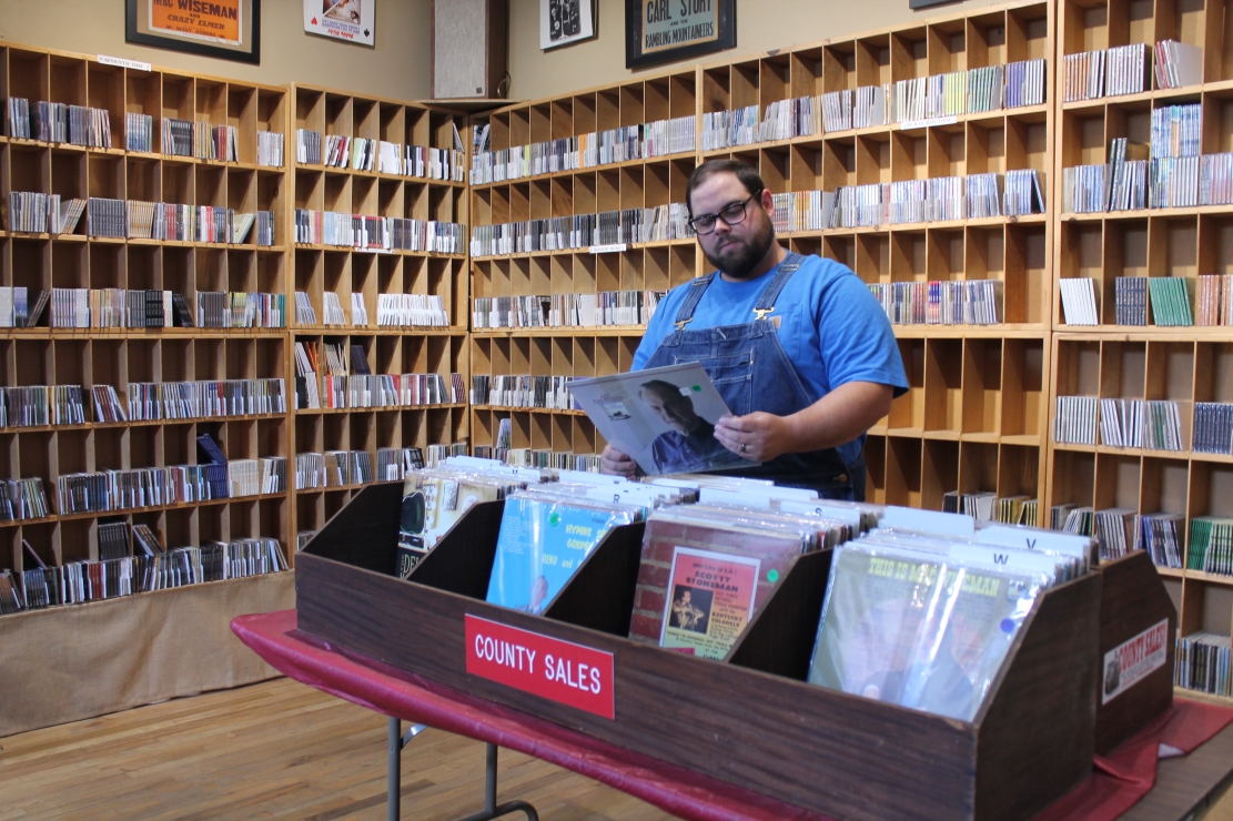 Man standing in the middle of a record shop, browsing through the bins.