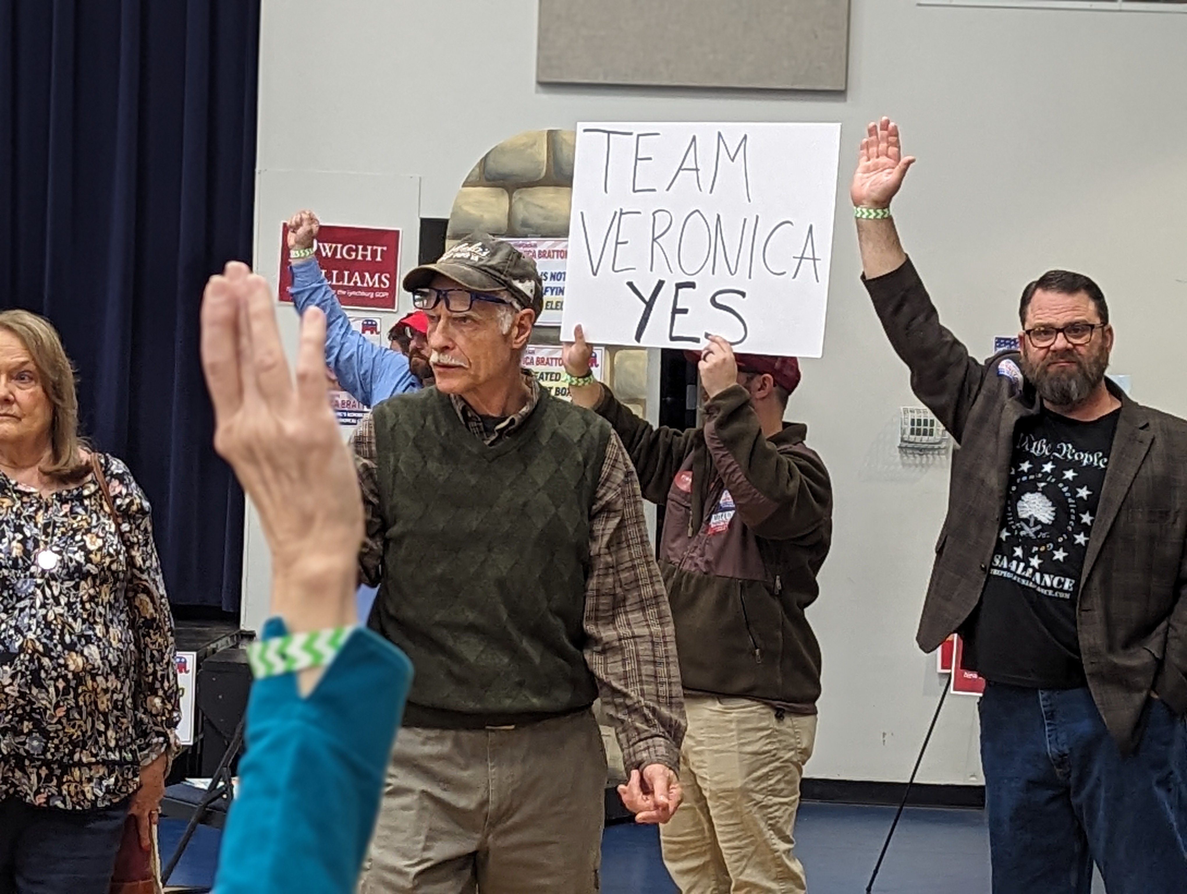 Men raising their hands at a political meeting.