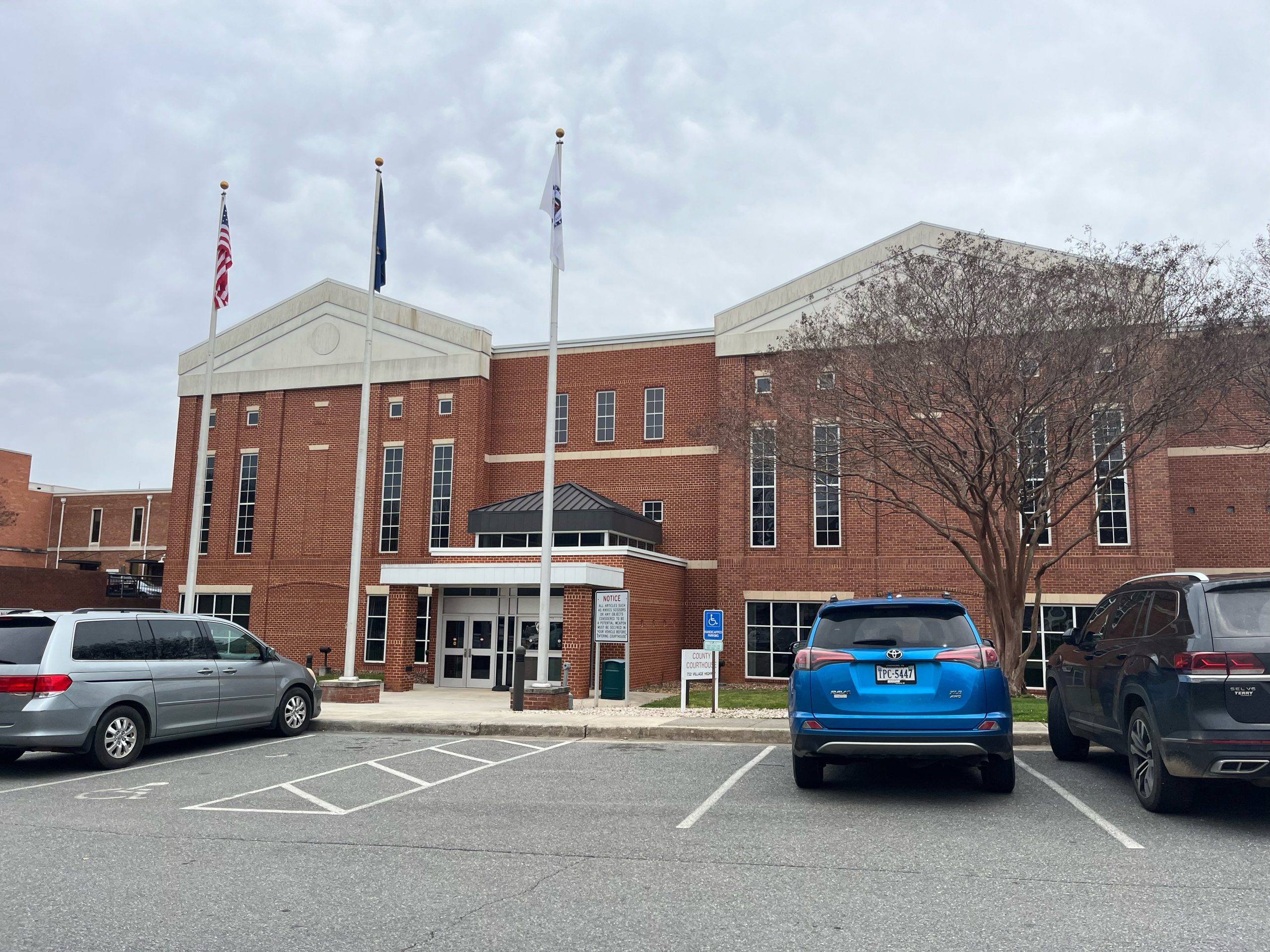 exterior of Campbell County courthouse, a red brick building with three flags flying in front.