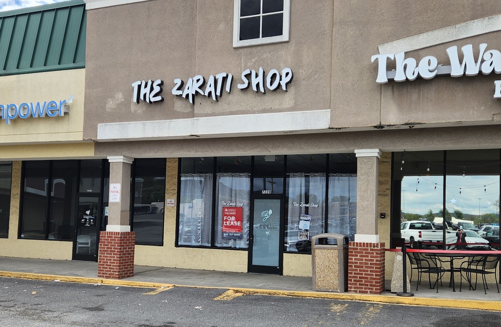 A vacant storefront in a strip mall with the sign "The Zarati Shop" over the door.