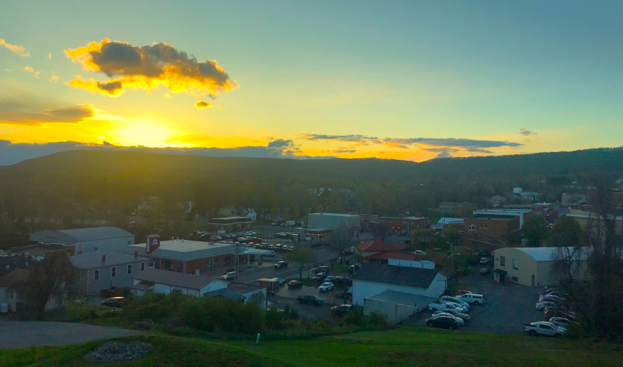 The view from the deck of Living Proof Beer Company reveals the sun sinking over Rocky Mount, with the Harvester Performance Center shown in the lower center left.