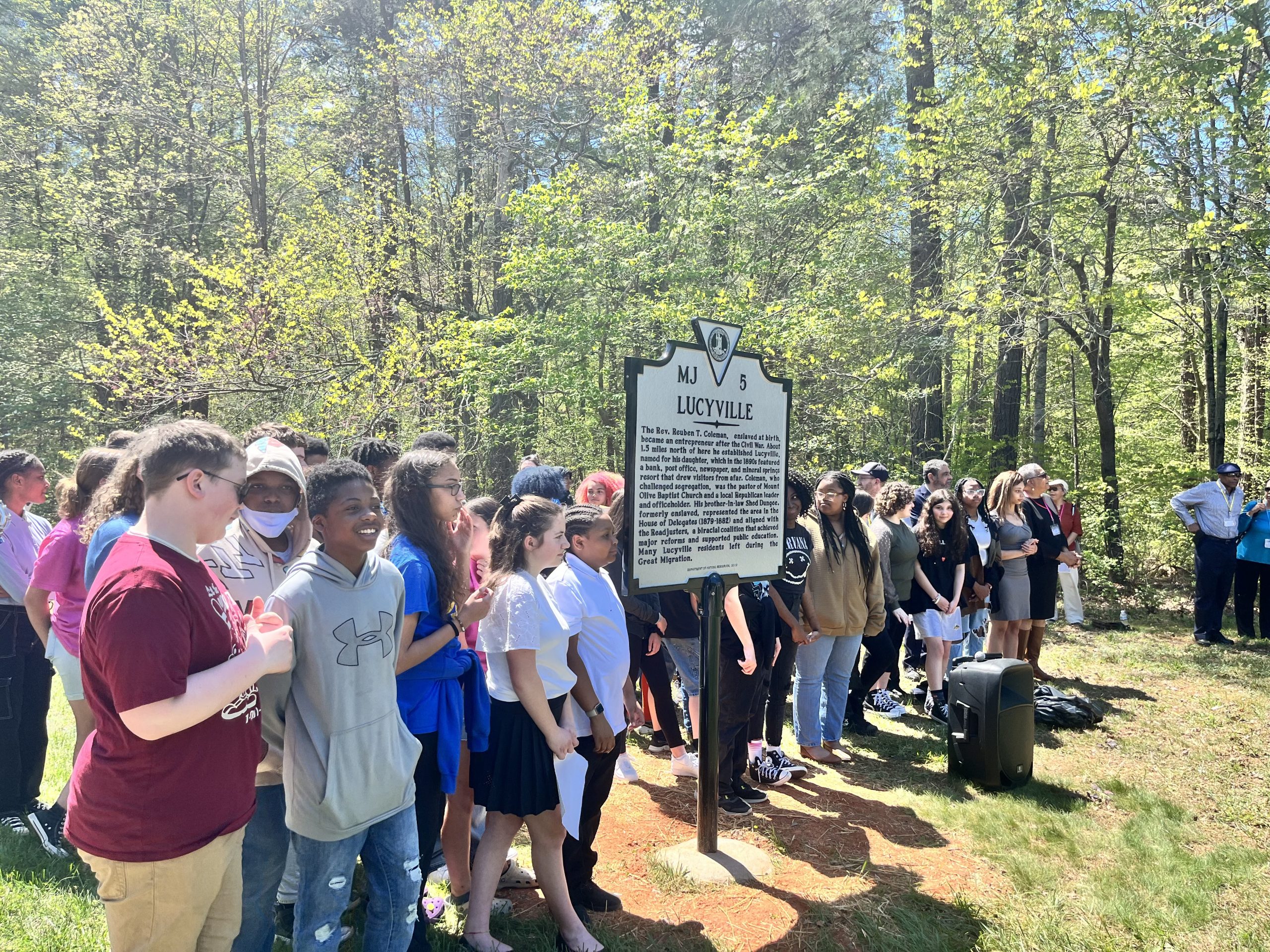 A group of students stands around a historical marker