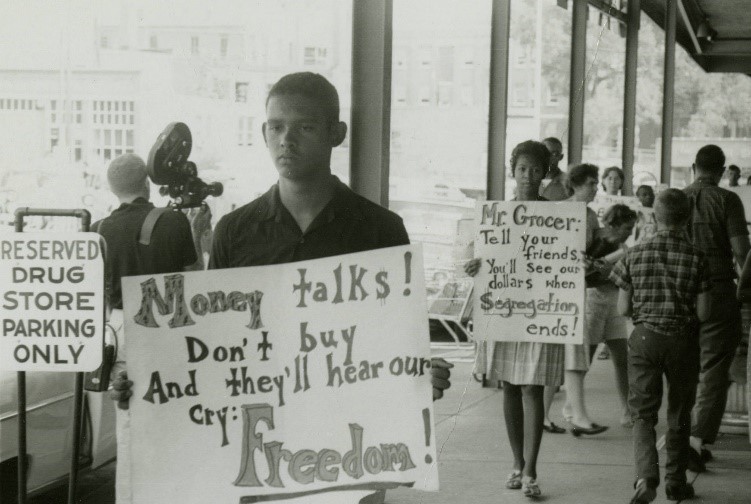 Black and white photo of students marching, holding signs decrying Massive Resistance and segregation.