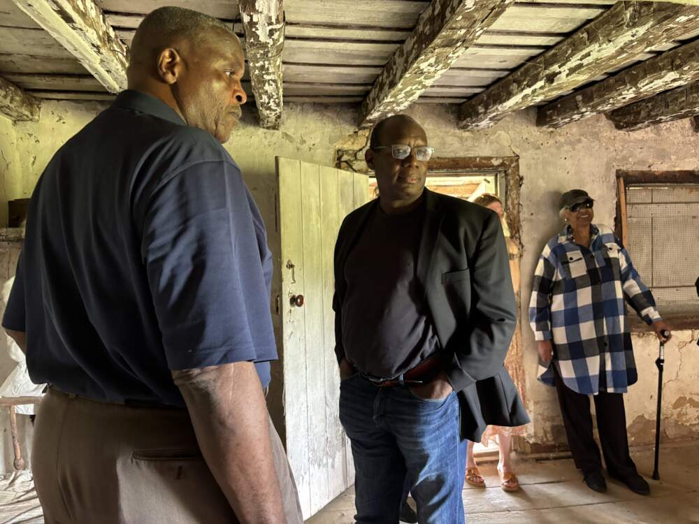 Two men and a woman standing inside an old slave house.