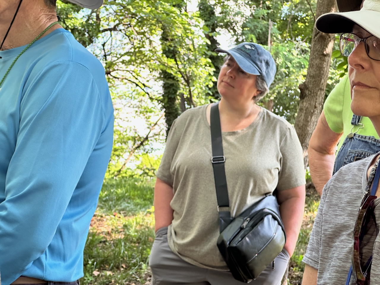 Suzanne Dorsett, wearing a t-shirt and a blue ball cap, stands in the Old Lick Cemetery.