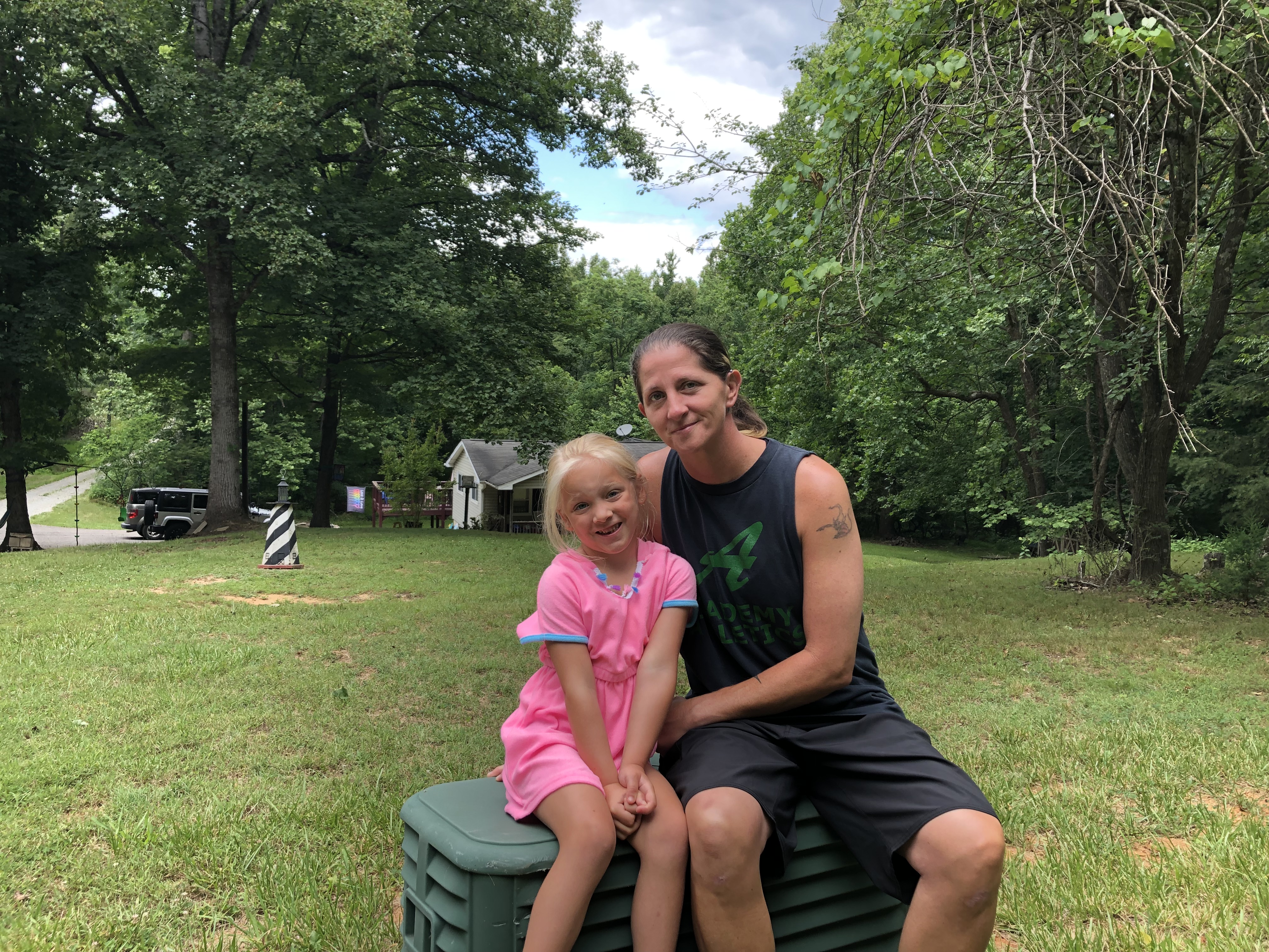 Mother and daughter Jessica Tipton and 5-year-old Lyrik sit on a green Cox Communications box in their yard. It eventually will supply internet to their home.