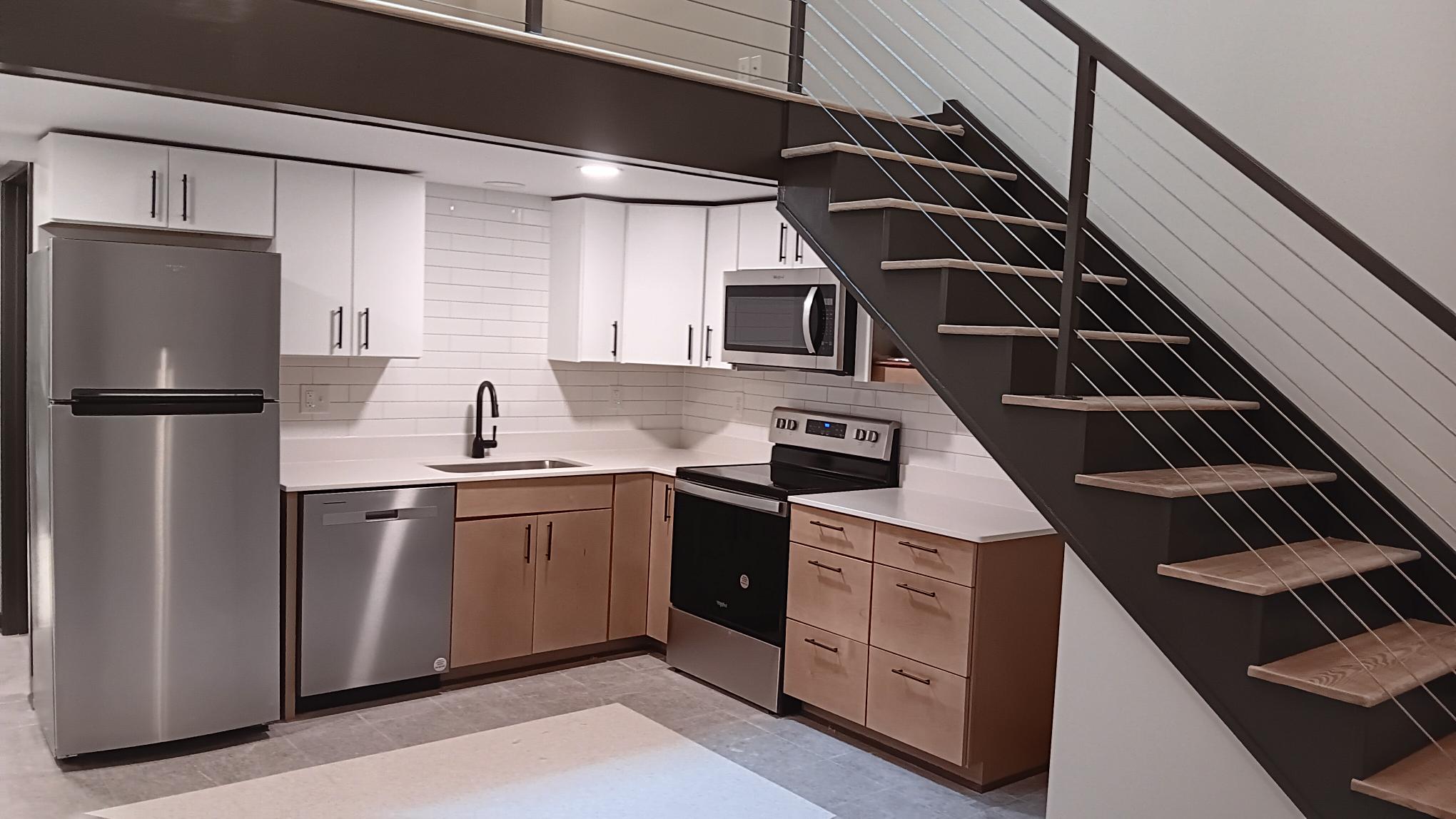 Interior of a loft apartment, showing the kitchen and stairs to the bedroom loft.