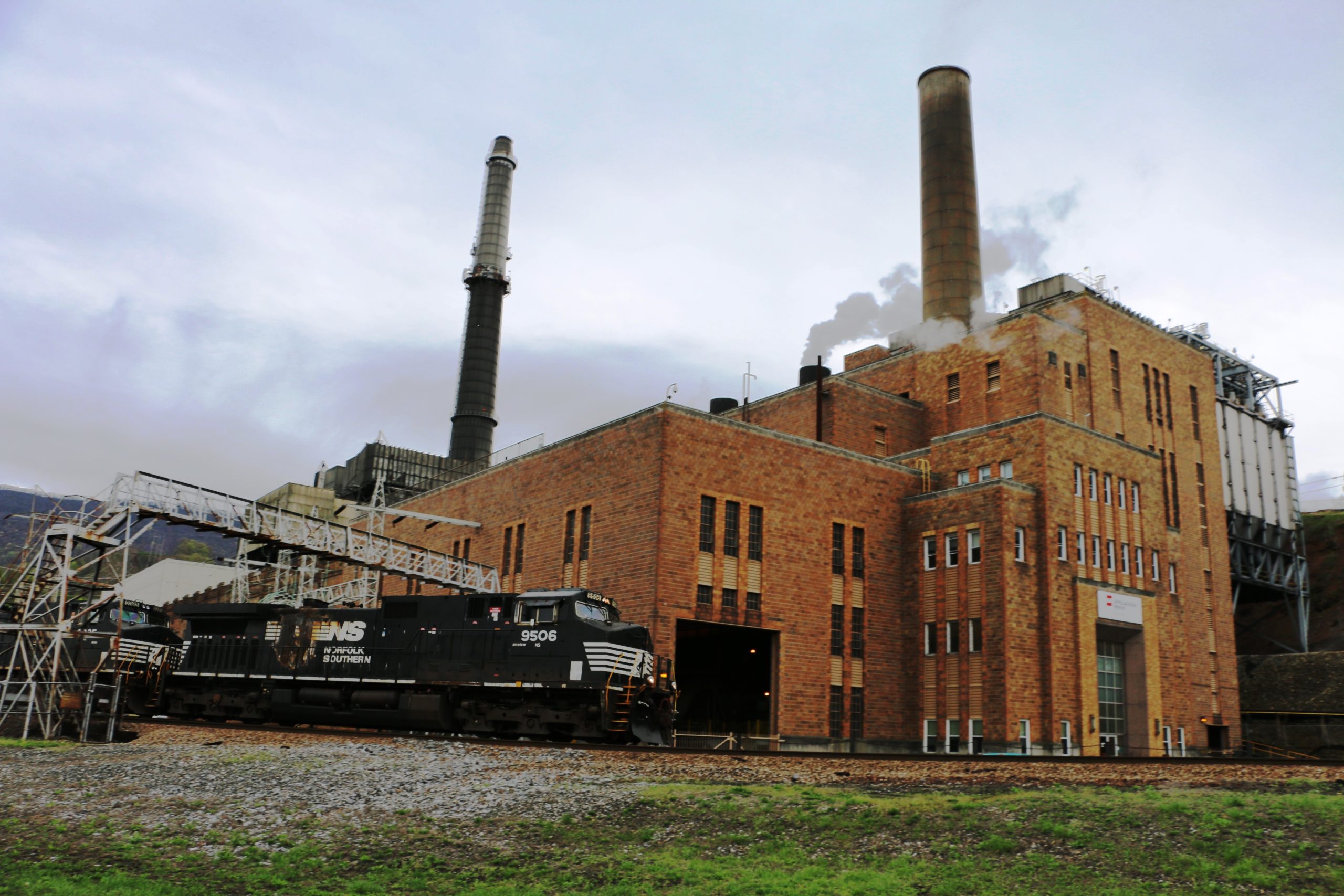 An old brick power plant with steam rising from the roof.