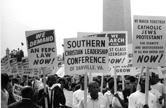 A crowd of protesters carrying signs at the 1963 March on Washington. One sign says "Southern Christian Leadership Conference of Danville Va"