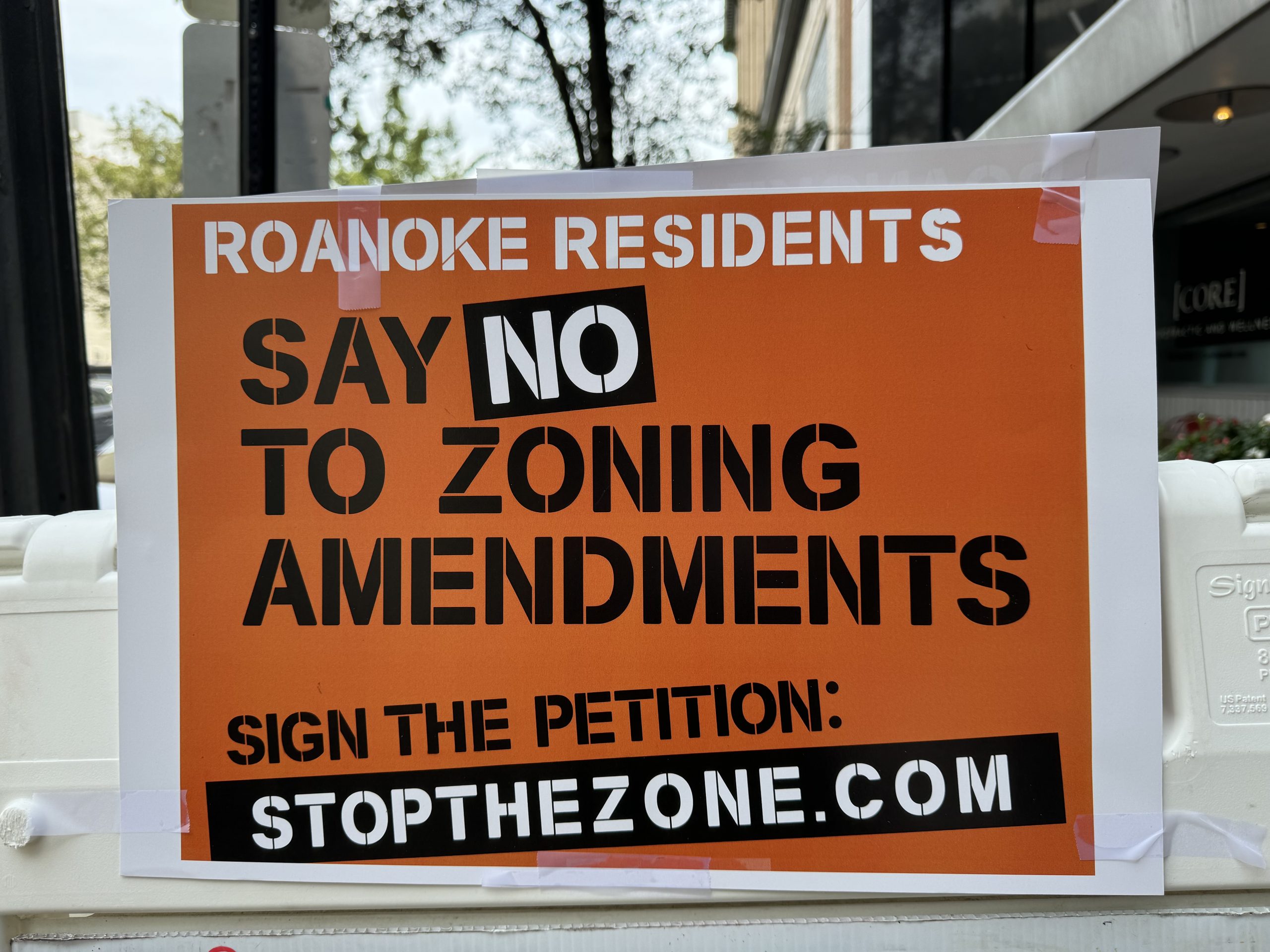 An orange sign with black lettering saying "Say NO to zoning amendments"