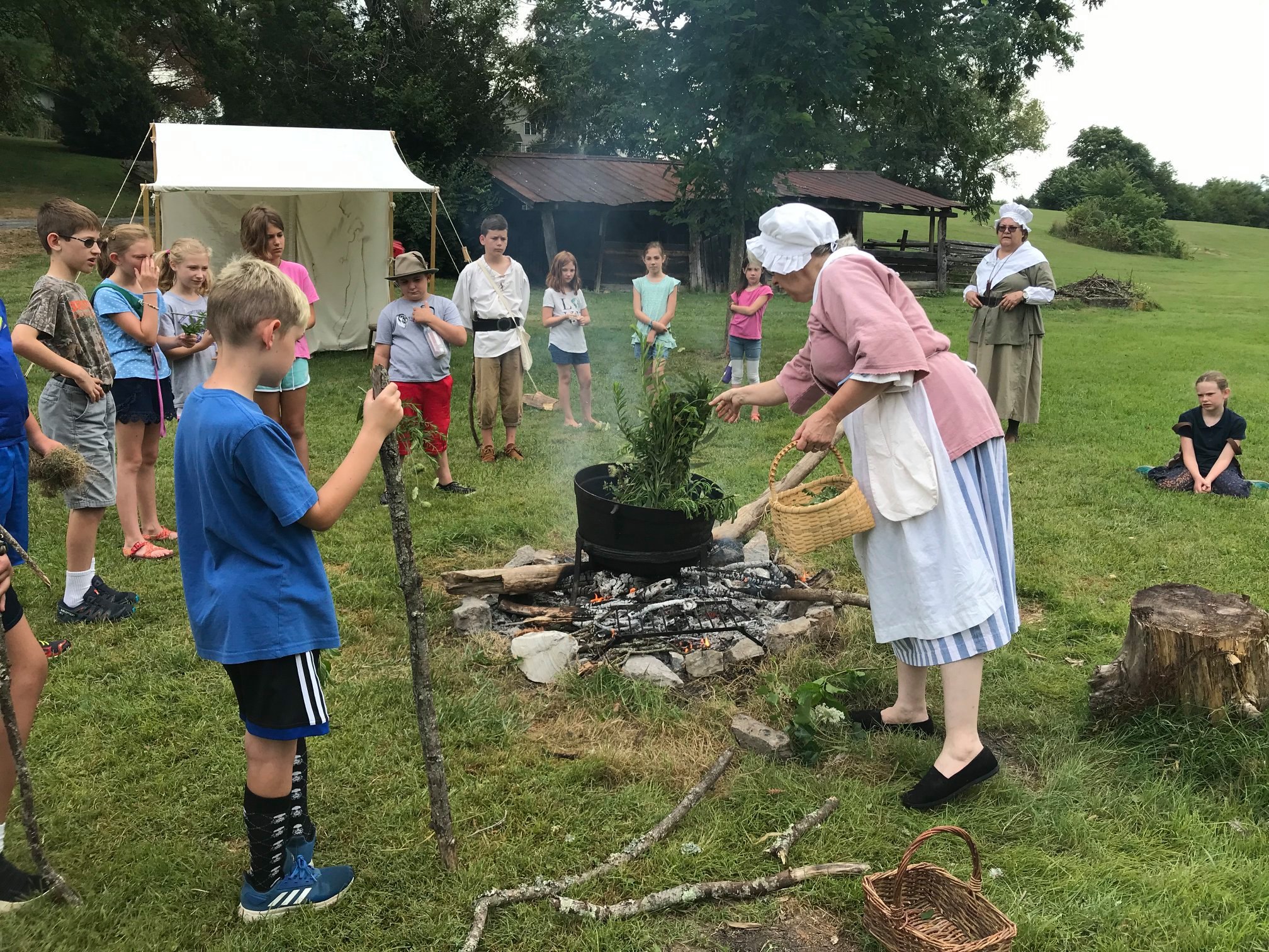 A reenactor demonstrates colonial cooking to visiting school children. Courtesy of Abingdon Muster Grounds.