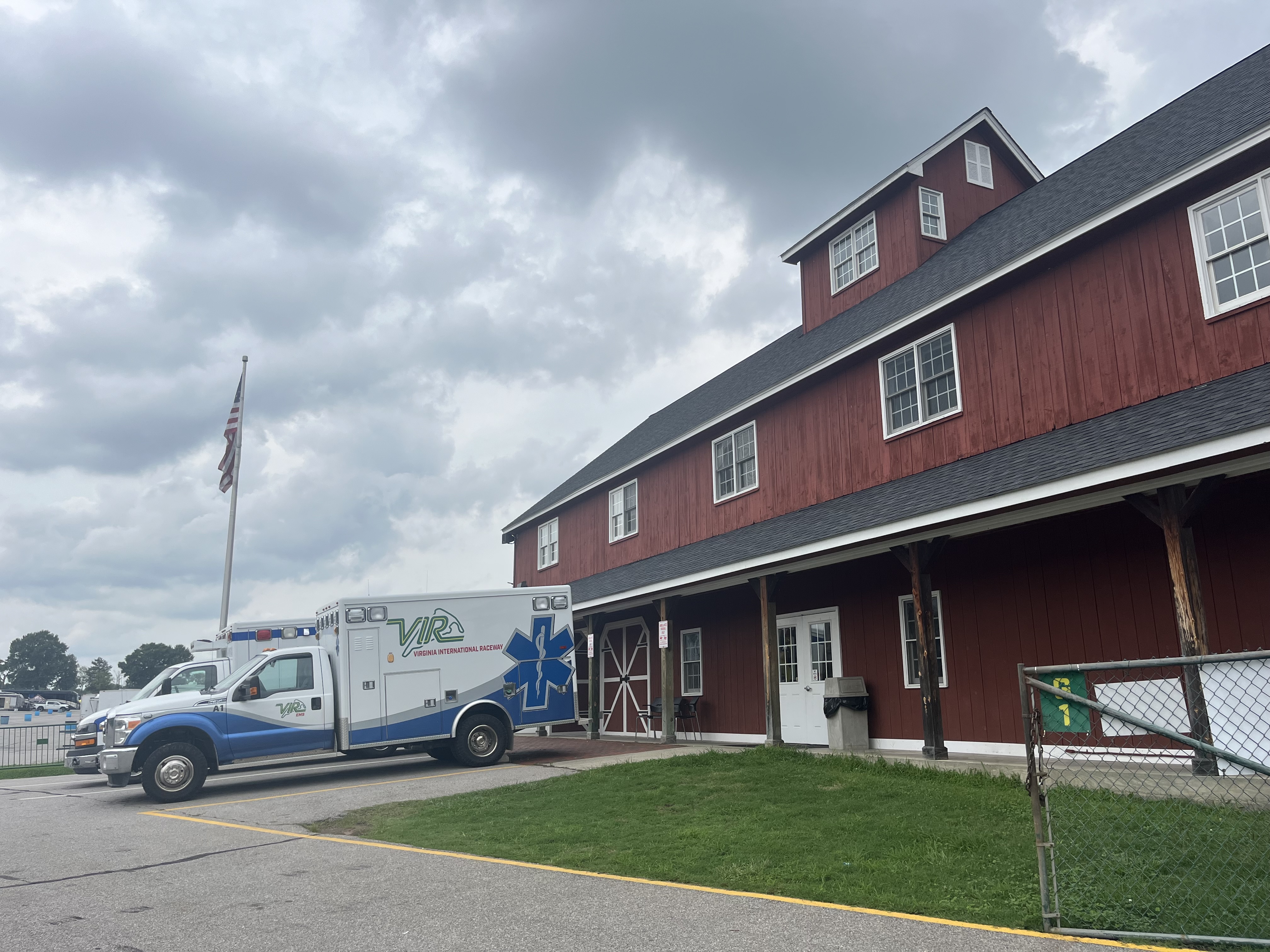 an ambulance is parked outside of a red building, the Virginia International Raceway's onsite emergency services department. 