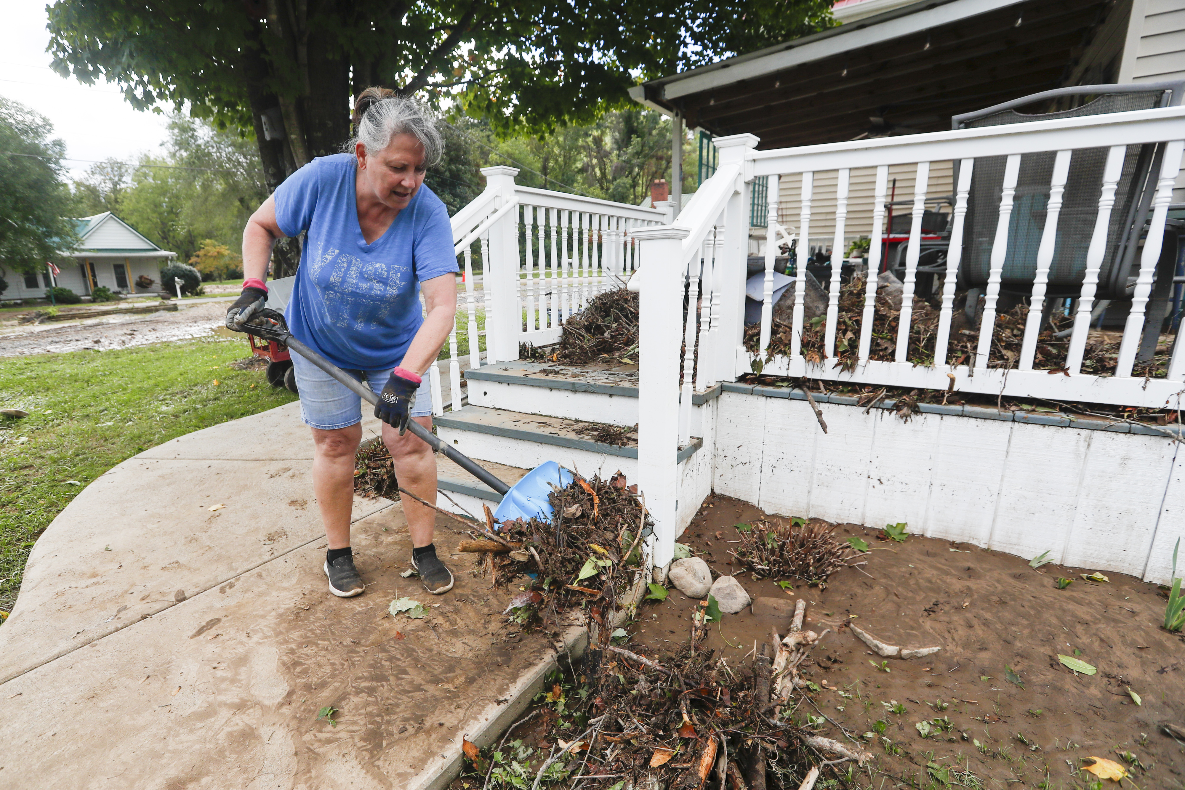 Susan Coleman shovels storm debris off the front porch of her home in Damascus.